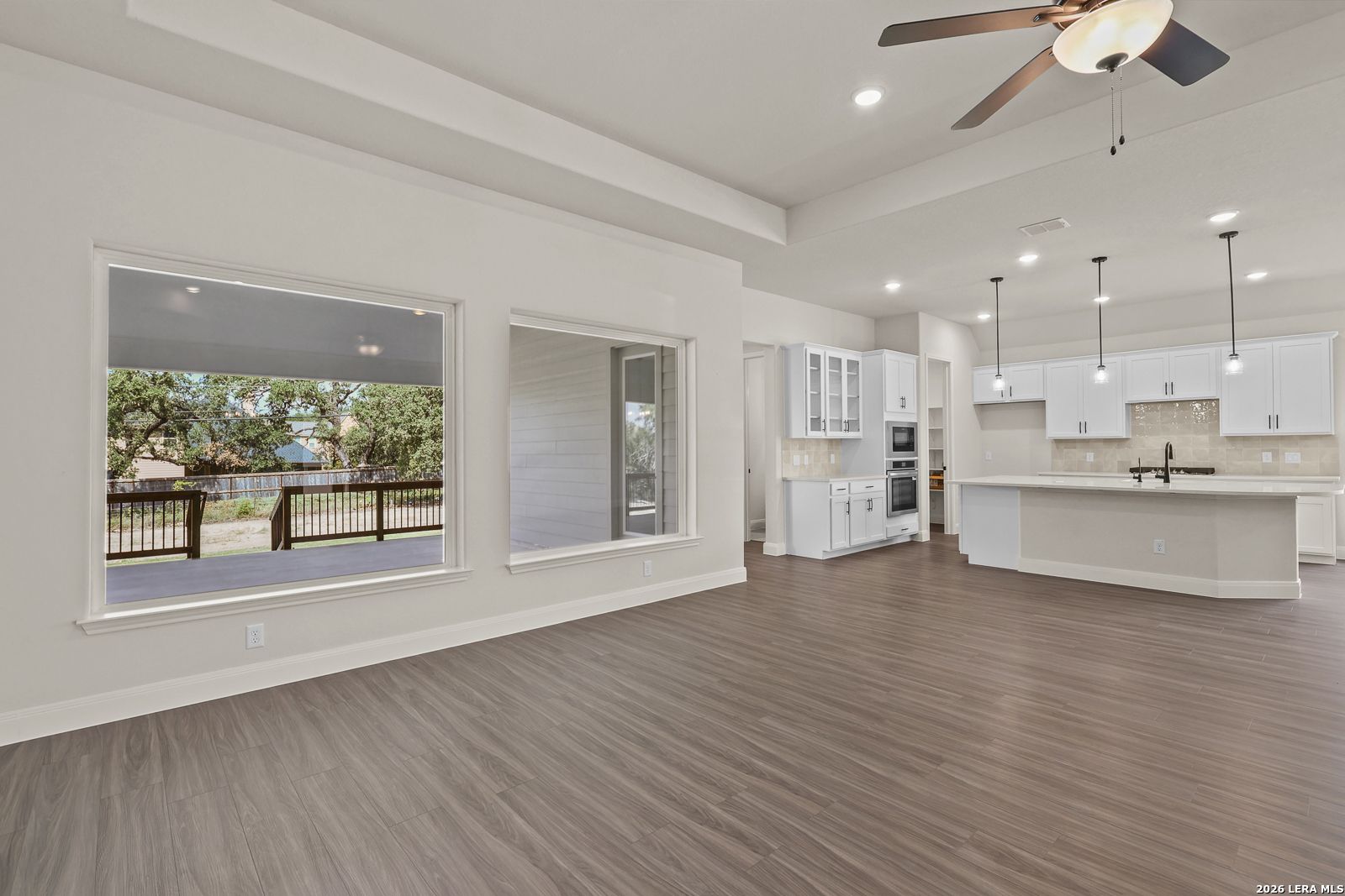 Open-concept living room and white kitchen in The Summerlin B floor plan at Potranco Oaks, Castroville, Texas.