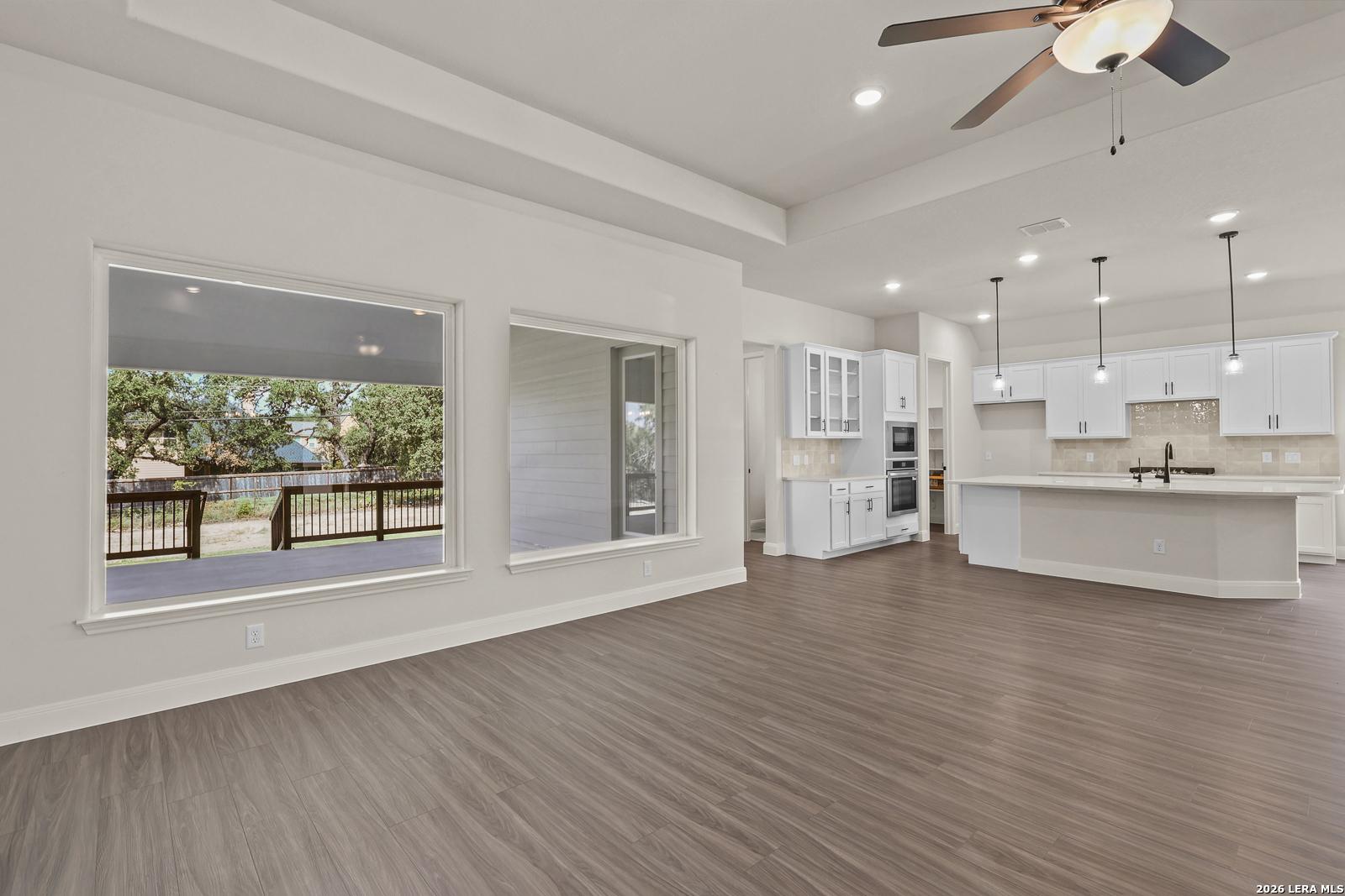Open-concept living room and white kitchen in The Summerlin B floor plan at Potranco Oaks, Castroville, Texas.