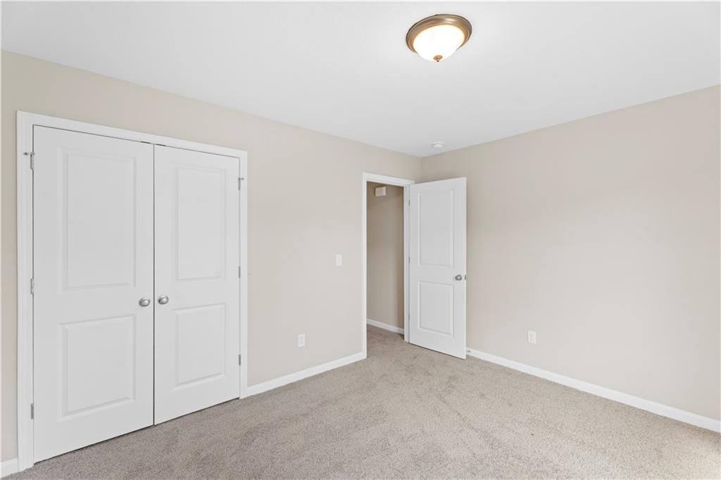 Bright bedroom with beige walls, gray carpet, double closet doors, and adjacent bath in Davidson Homes The Washington, Phenix City