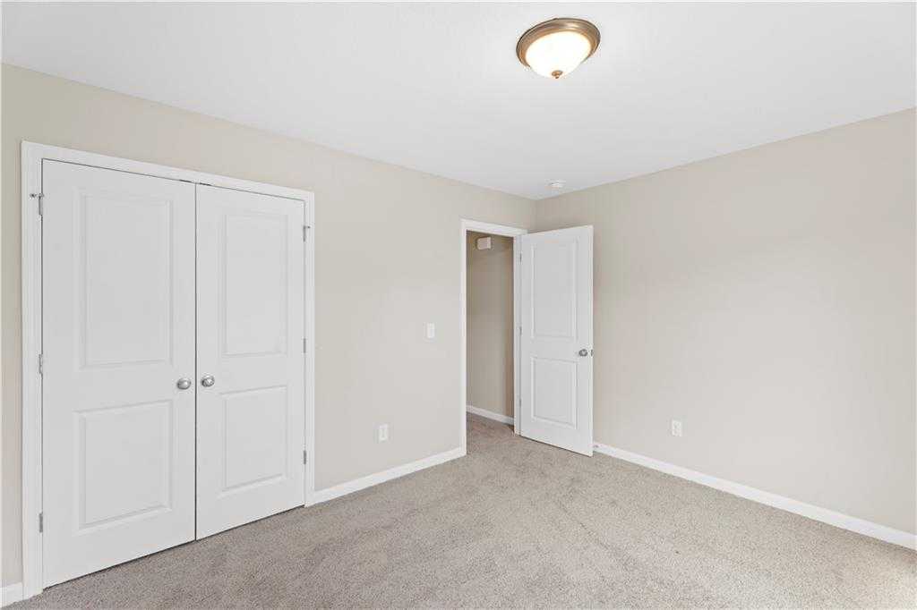 Bright bedroom with beige walls, gray carpet, double closet doors, and adjacent bath in Davidson Homes The Washington, Phenix City