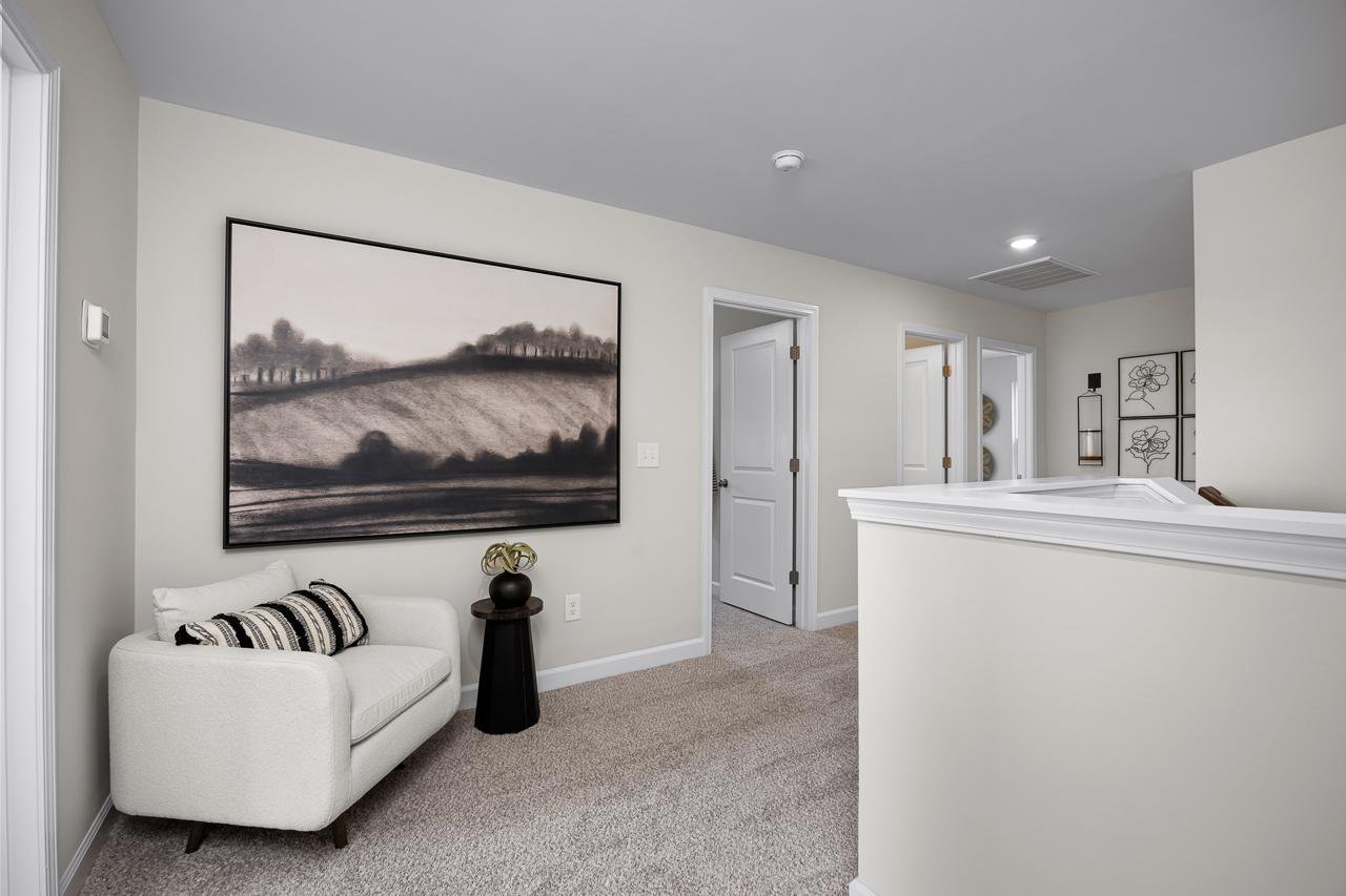 Cozy upstairs loft nook with striped armchair, potted plant, and large abstract landscape artwork in Wellers Knoll, Lillington NC