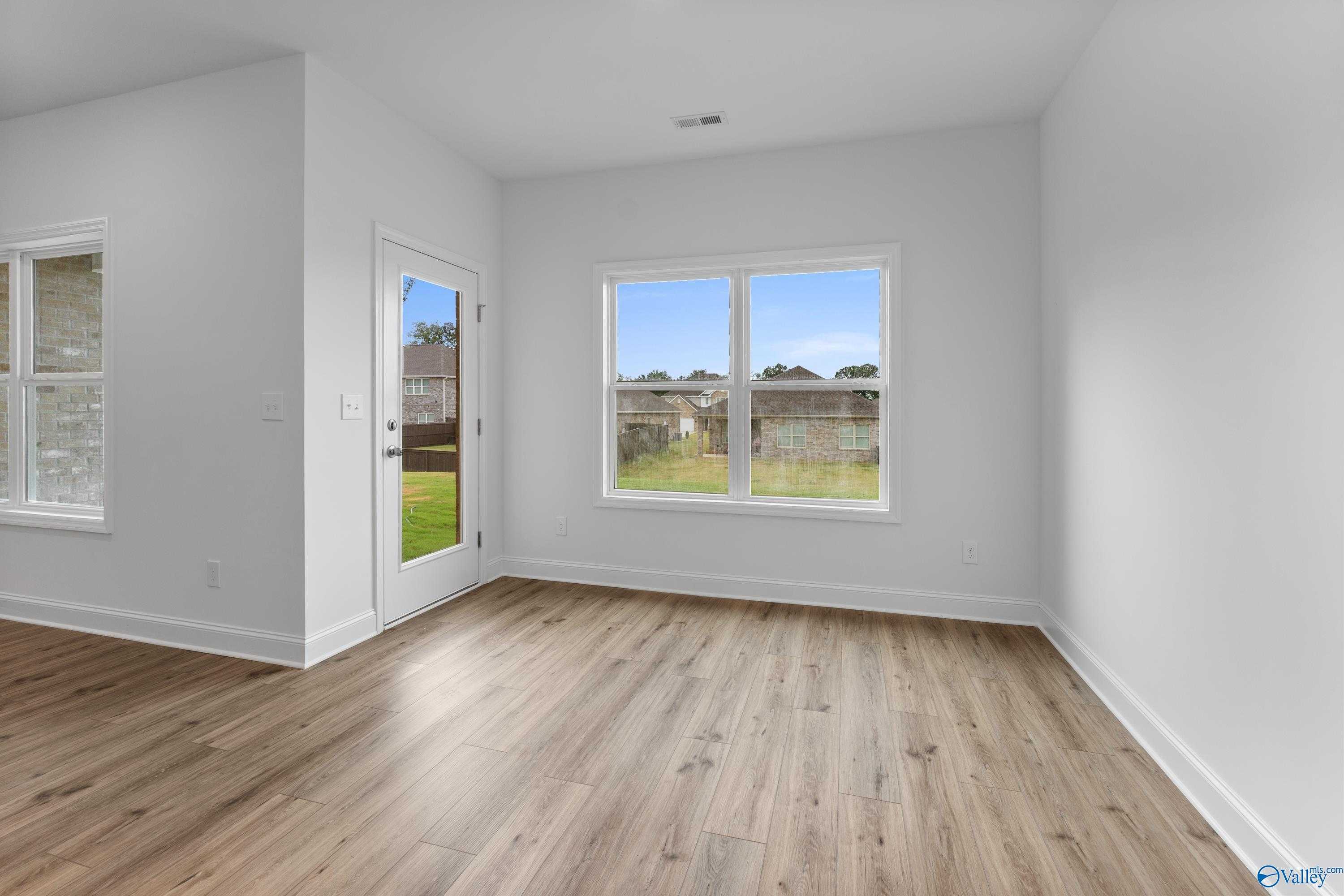 Bright sunroom with hardwood floors, French doors, and scenic backyard view in Davidson Homes The Asheville C, New Market, Alabama