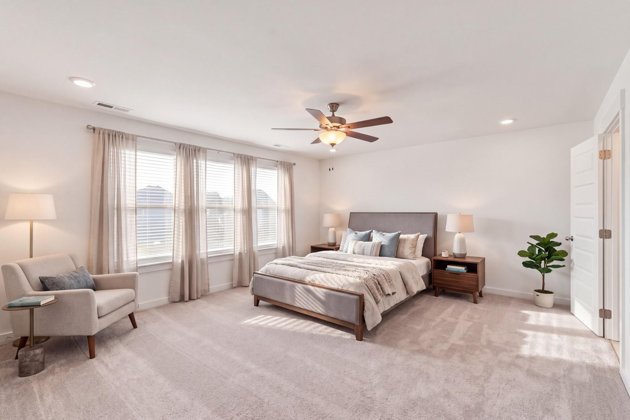 Bright primary bedroom with ceiling fan, large windows, and sitting area in Davidson Homes The Willow C, Woods Crossing, Gallatin TN