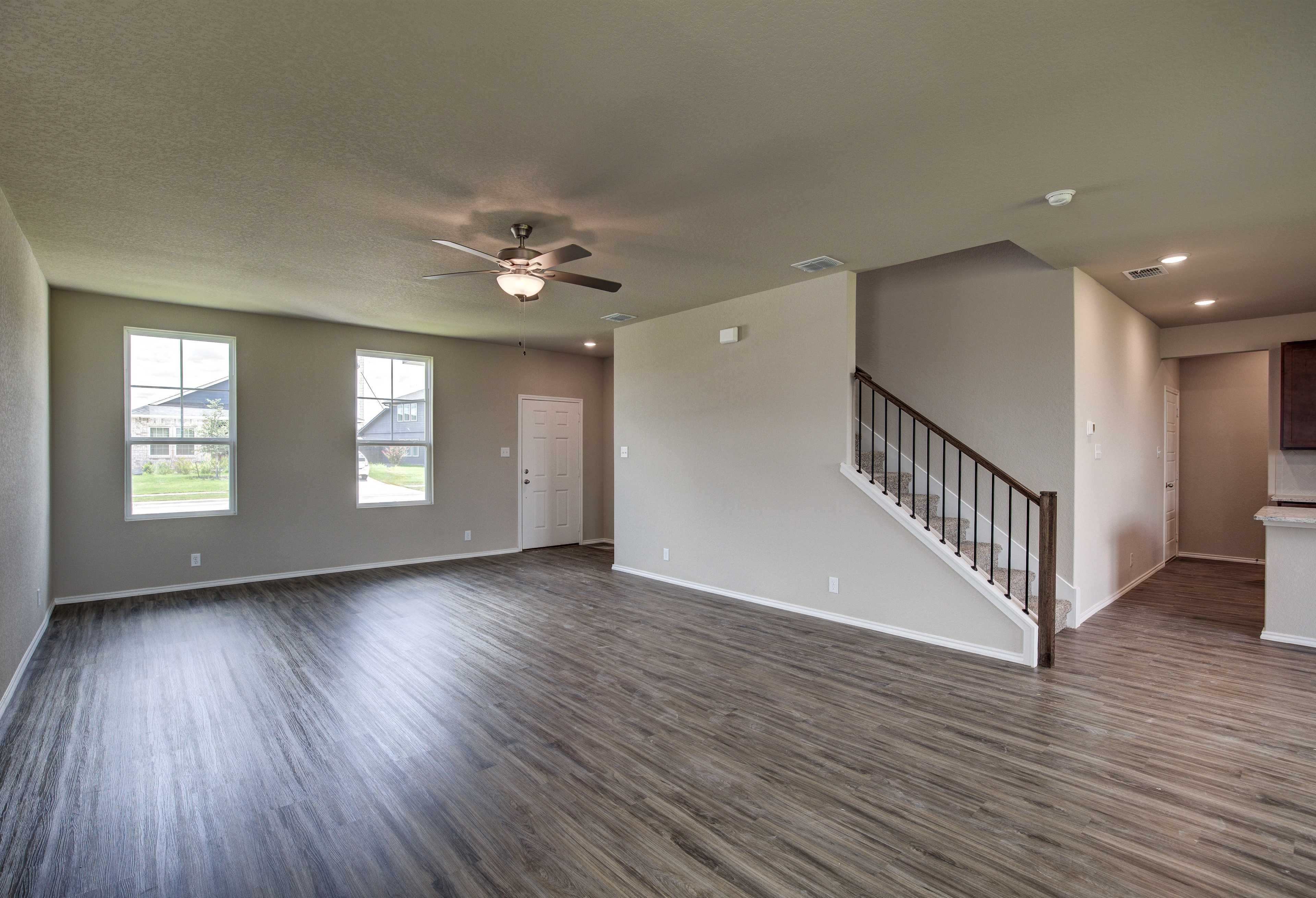 Spacious open-concept foyer in The Murray floor plan featuring hardwood floors, ceiling fan, large windows, and ascending staircase