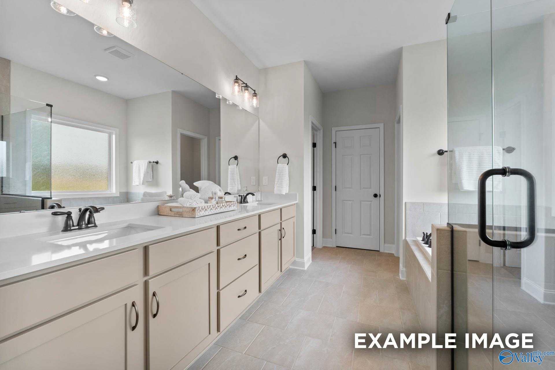 Modern master bathroom with double vanity, large mirrors, and glass shower enclosure in Davidson Homes The Kirkland, Decatur, Alabama