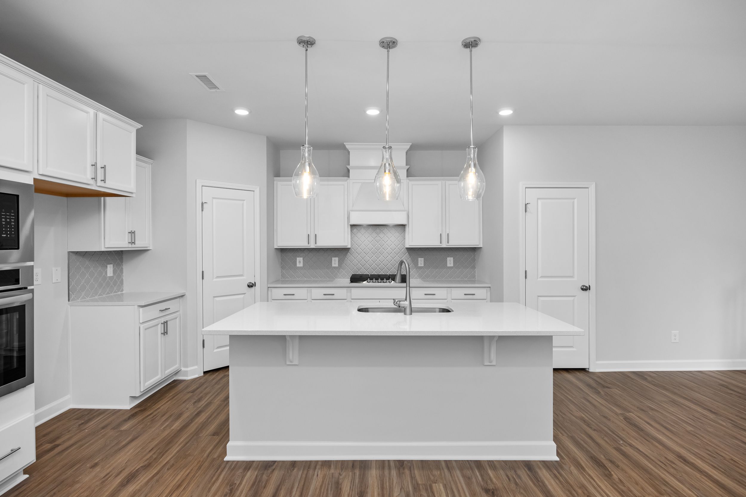 Modern kitchen in The Durham featuring white cabinetry, quartz island, and stylish pendant lighting in Lillington, NC.