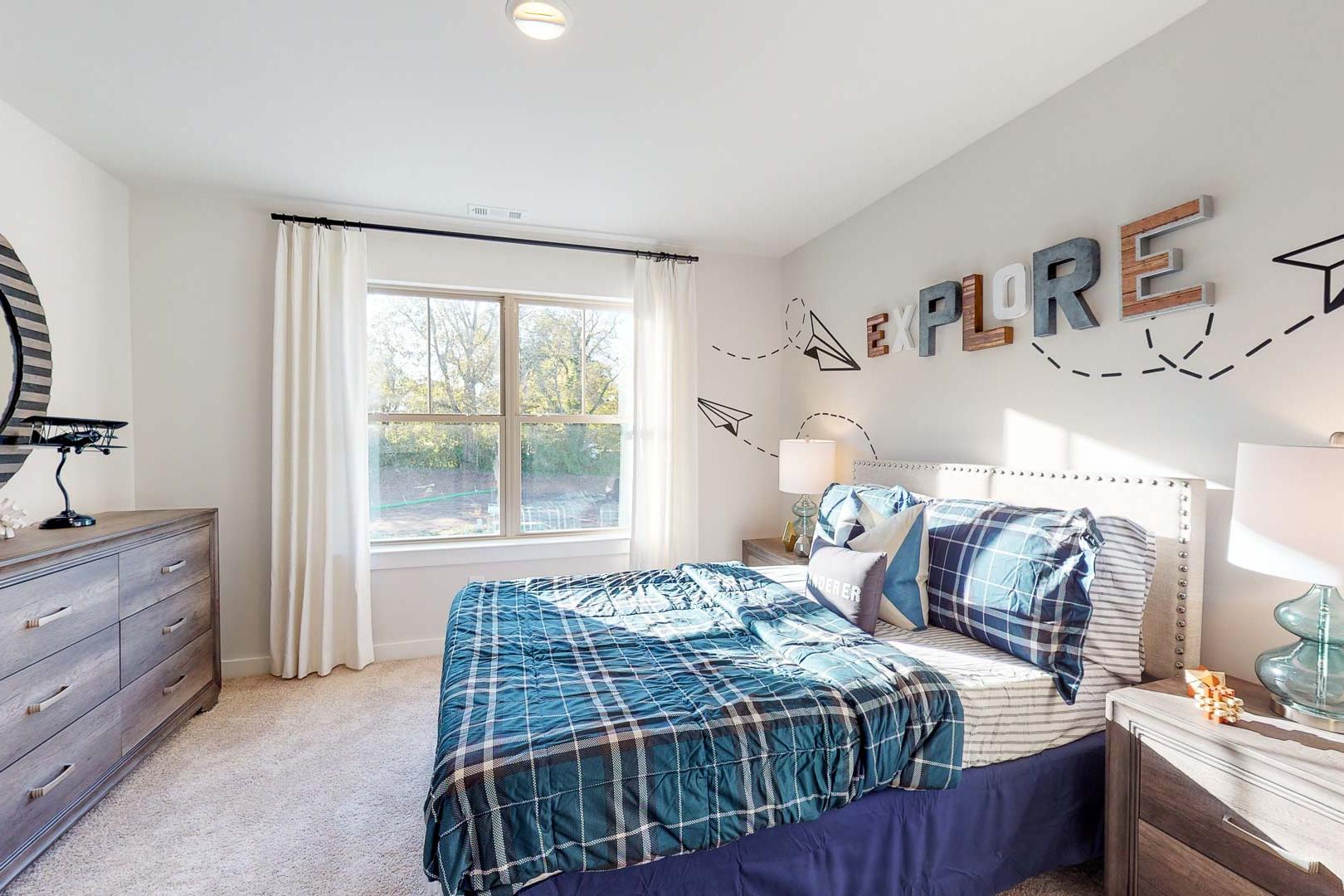 Child's explore-themed bedroom at Liberty Creek in Gallatin TN featuring blue plaid bed, airplane wall decor and dresser