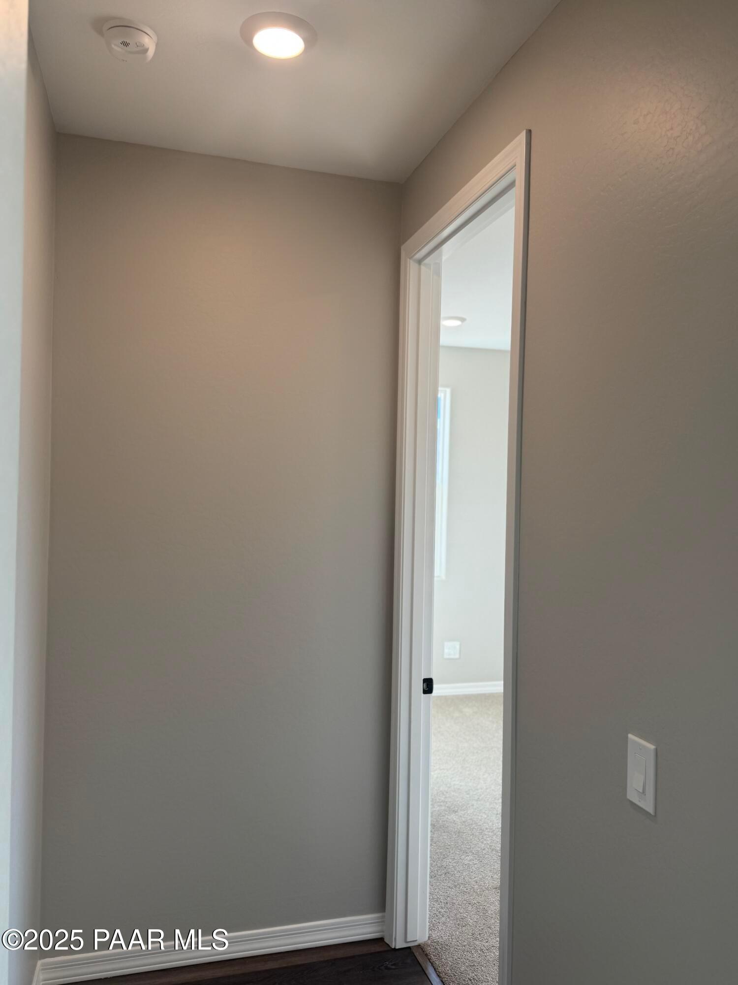 Neutral hallway with beige walls, recessed lighting, and open door to carpeted room in Davidson Homes The Monarch E, Prescott Arizona