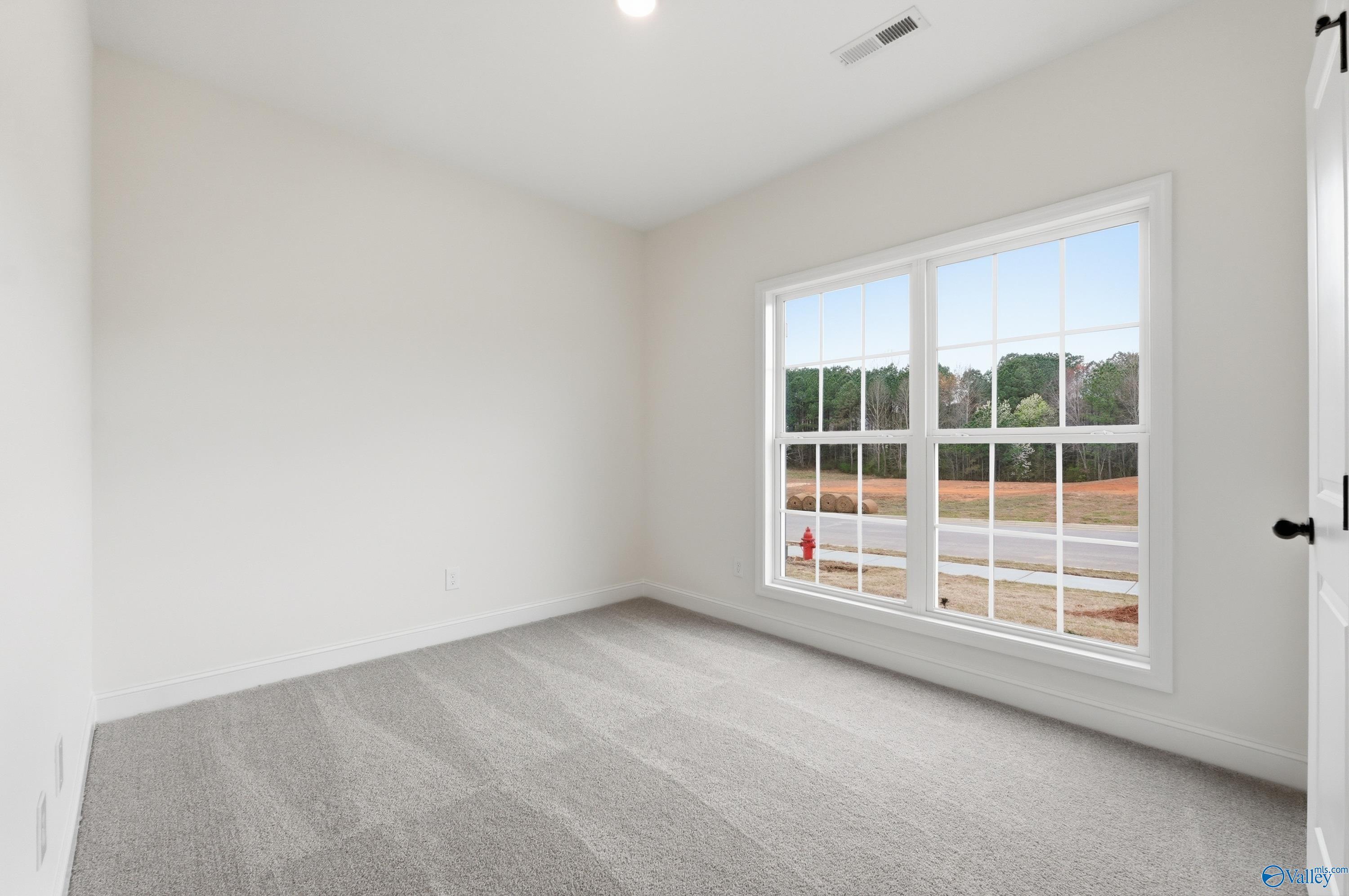 Bright bedroom with neutral carpet and large windows in The Asheville C floor plan at The Highlands in Arab, Alabama.