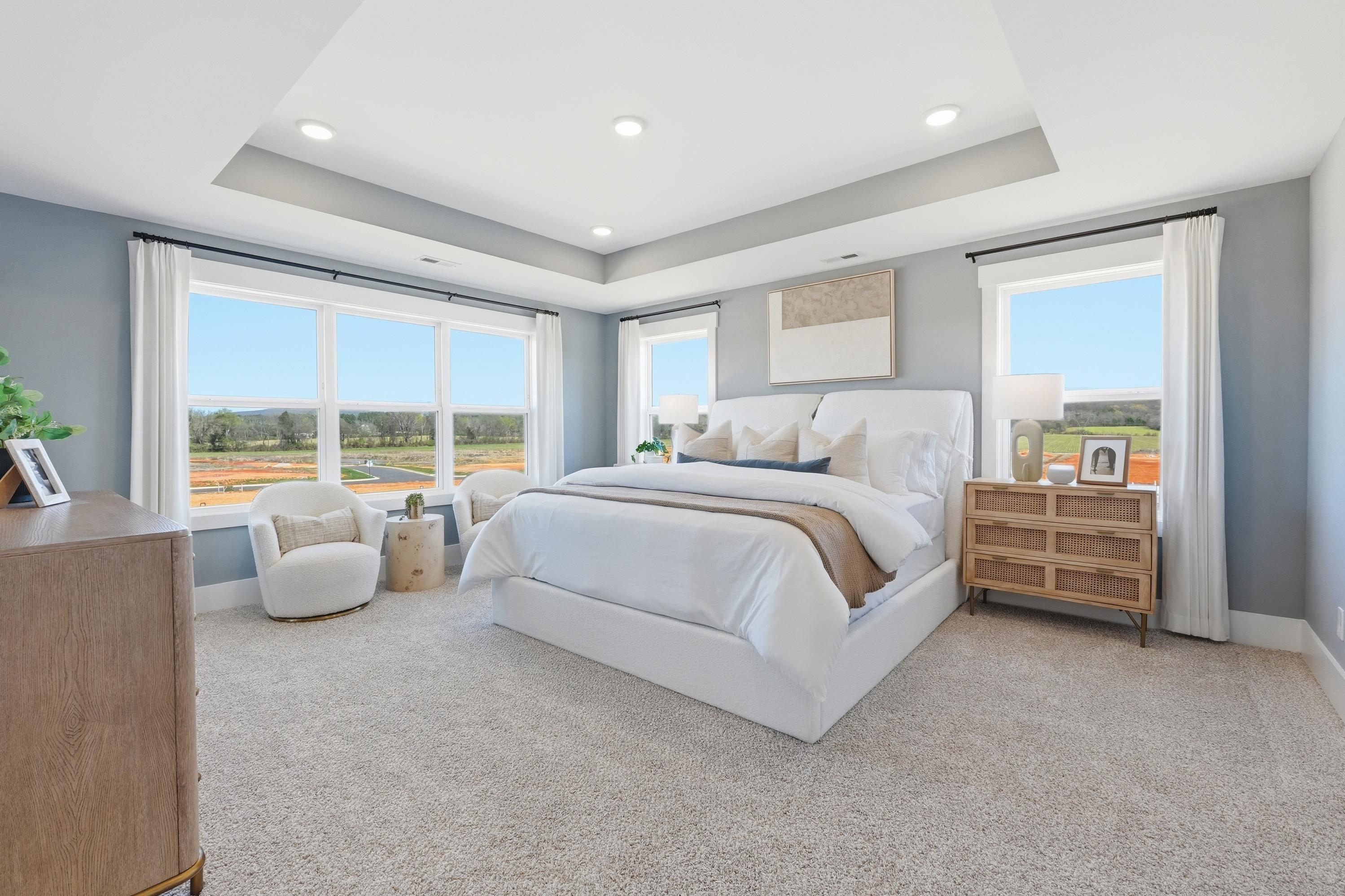 Bright master bedroom in Berry Cove, New Market Alabama with king bed, large windows, neutral tones and armchair