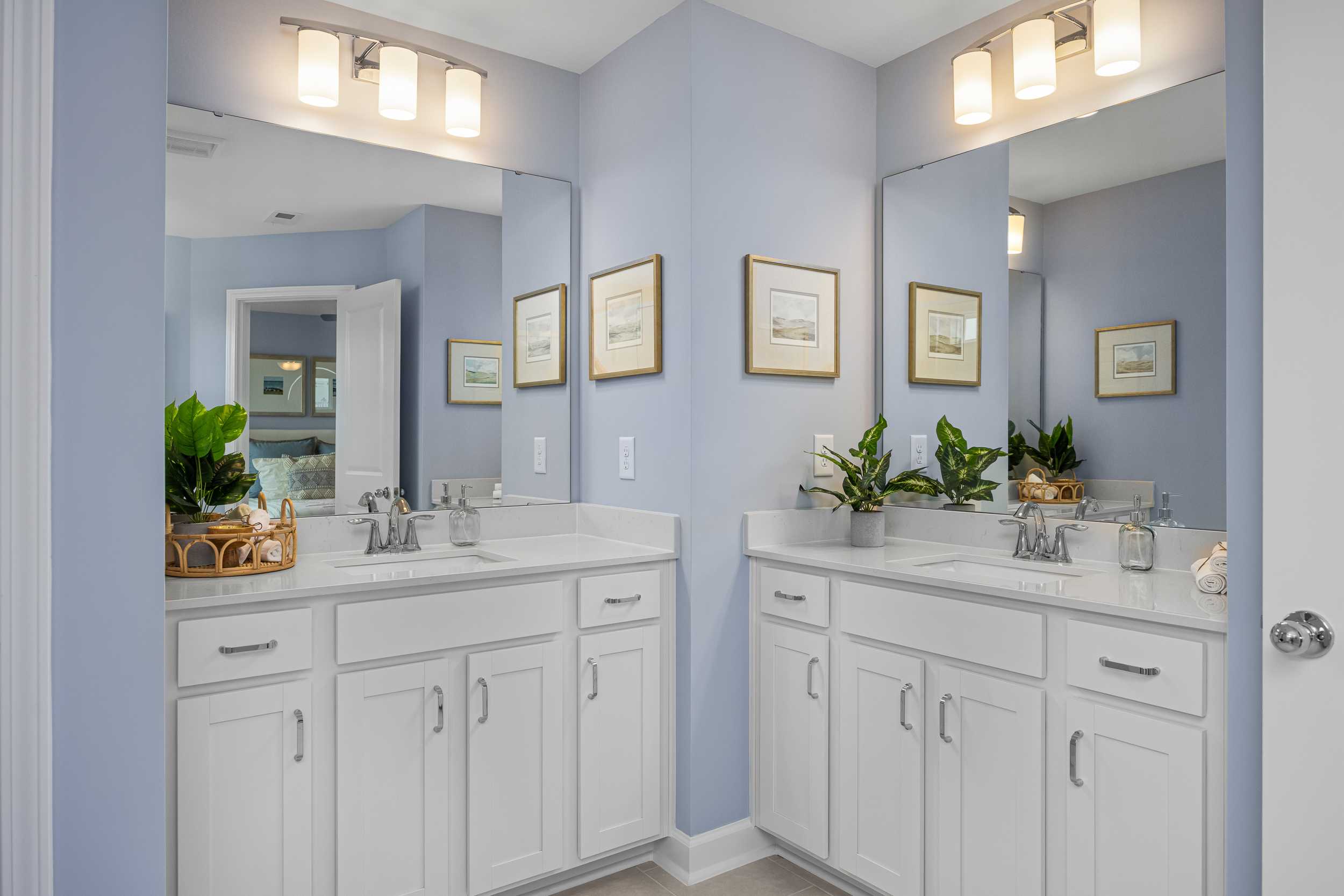 Spacious master bathroom at Springvale in Fuquay-Varina NC with dual white vanities, mirrors, blue walls, and potted plants