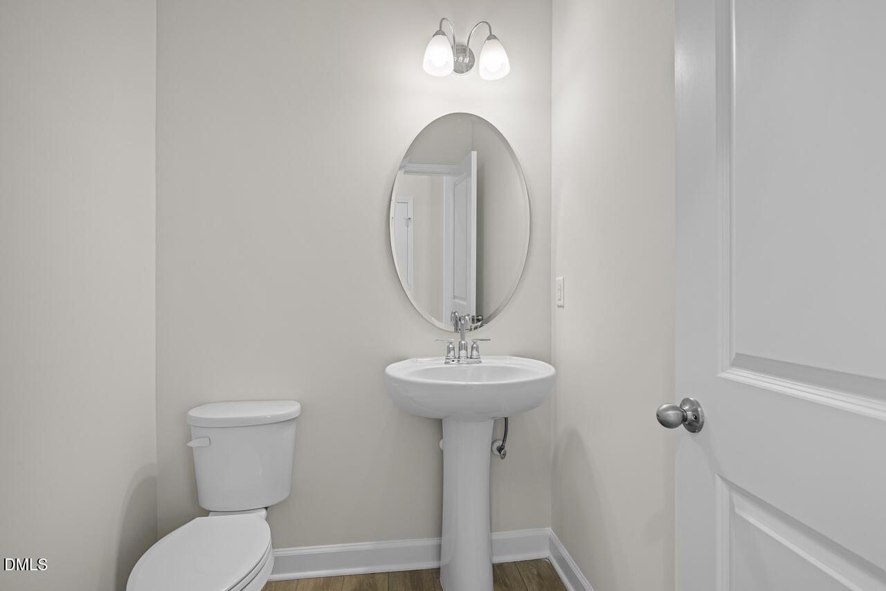 Modern half-bath with pedestal sink and oval mirror in The Gavin A floor plan at Gregory Village, Lillington, North Carolina.