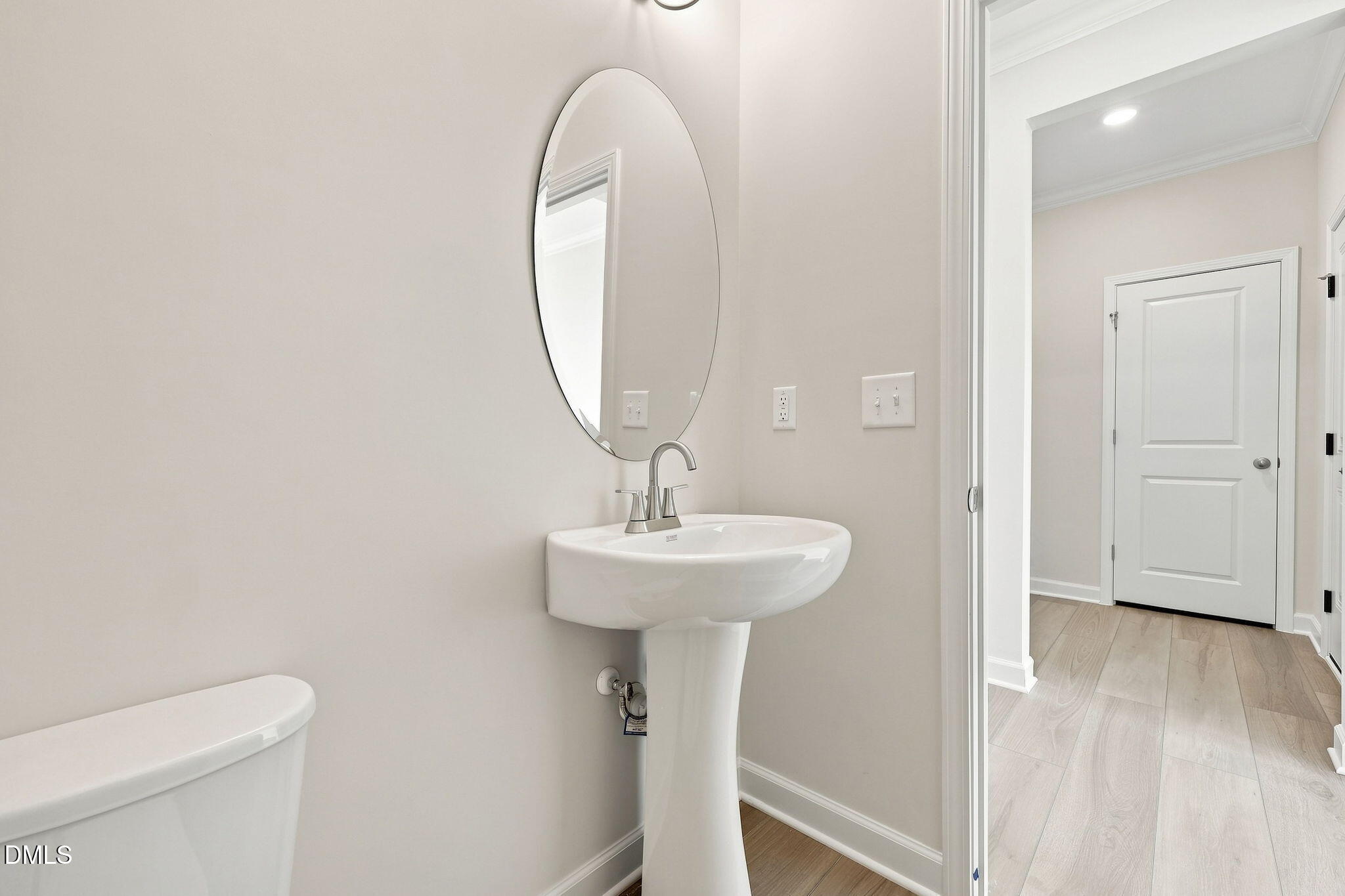 Modern half-bath with pedestal sink and oval mirror in The Magnolia B floor plan at Retreat at North Main, Lillington, NC.