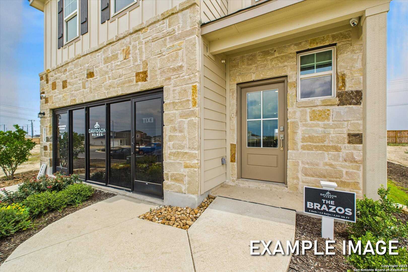 Modern two-story stone facade home with large garage door, entryway, and Brazos sign in Agave, San Antonio, Texas