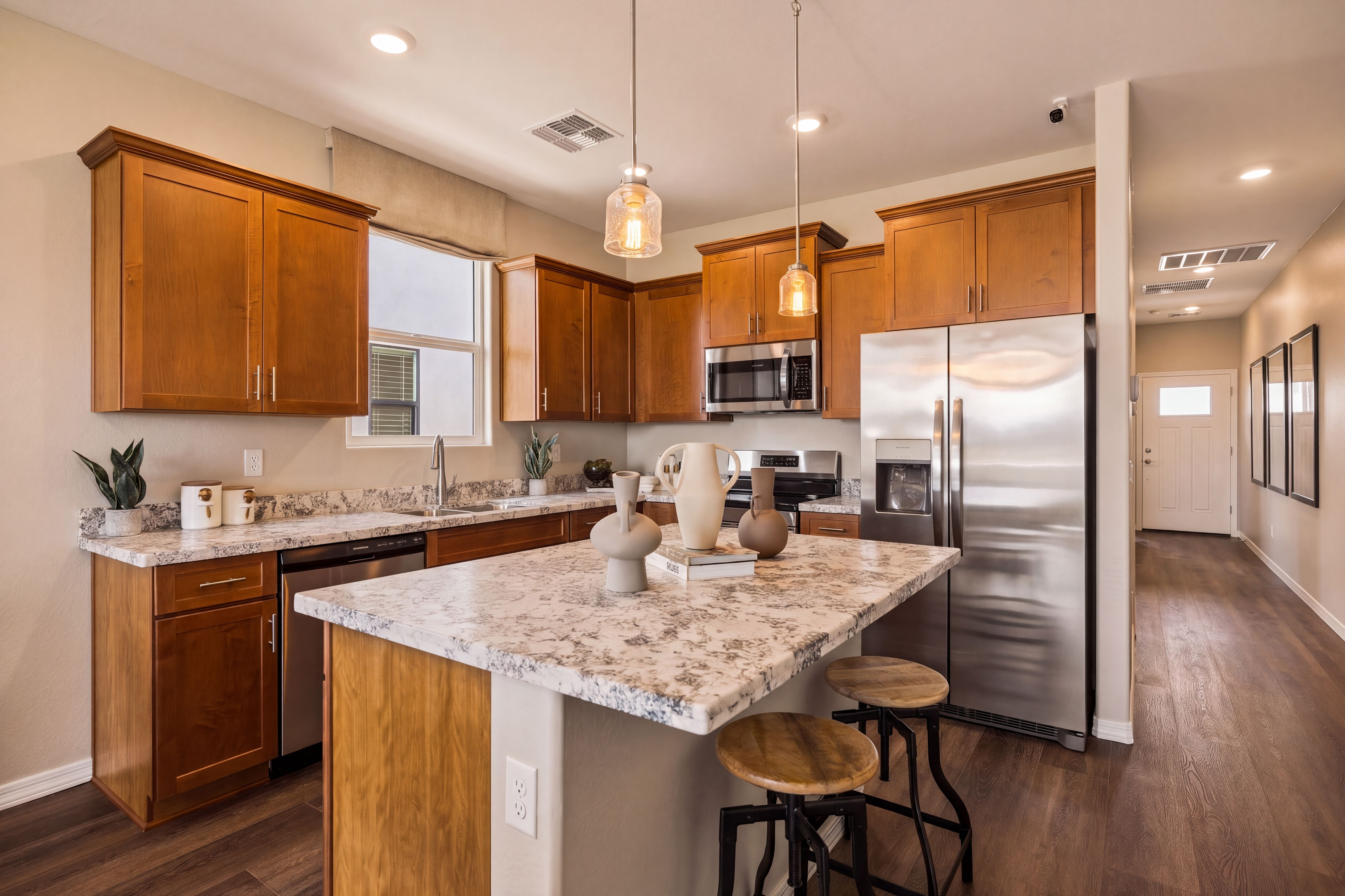 Kitchen with granite countertops, wooden cabinets, stainless steel appliances, and island seating at Senator Cottages by Davidson Homes in Prescott, AZ