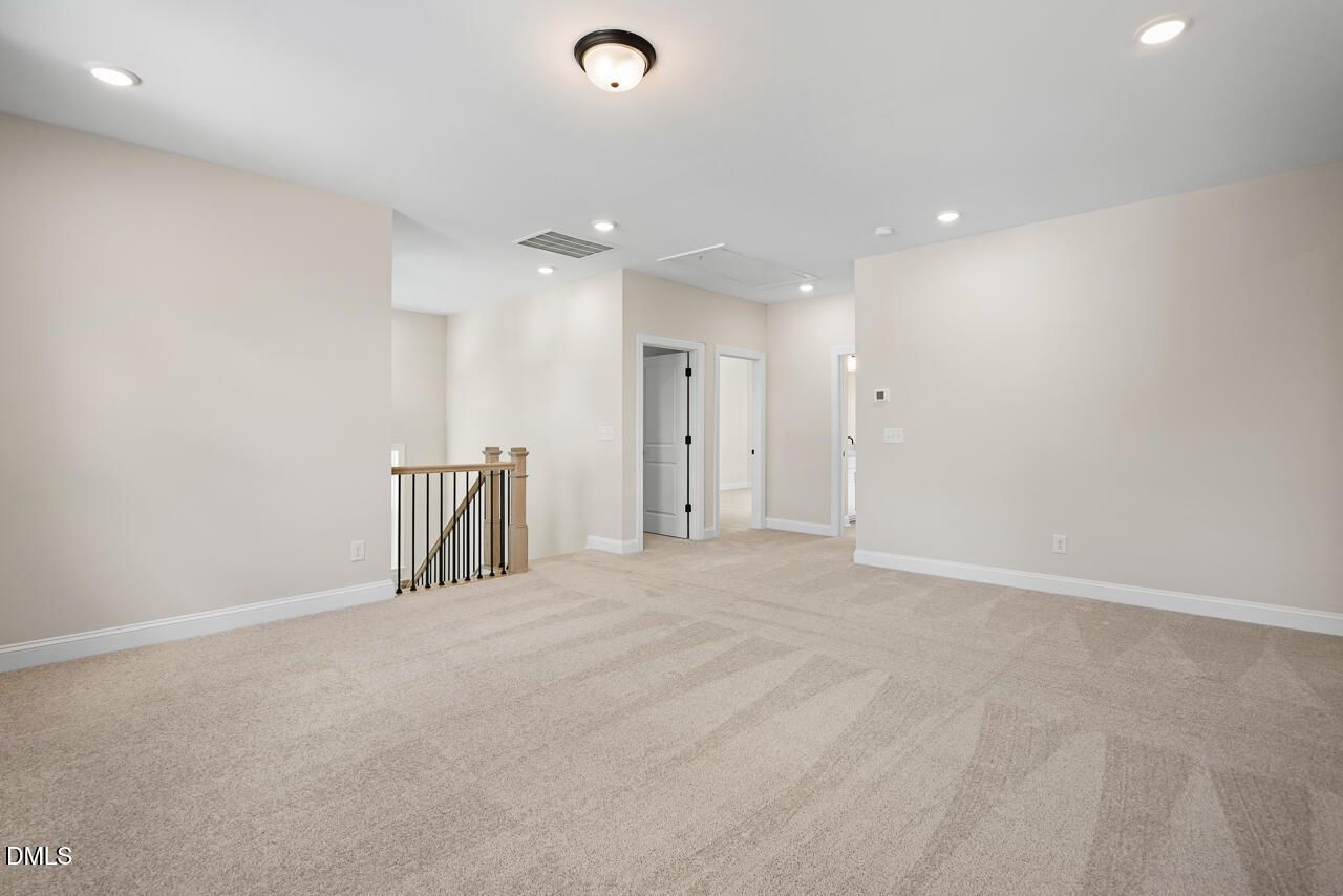 Spacious carpeted upstairs loft with staircase and recessed lighting in Davidson Homes Crawford D plan, Wake Forest, NC