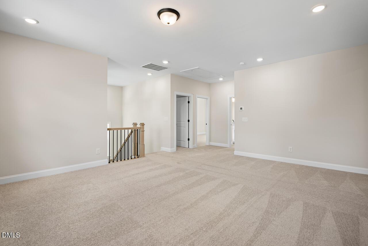 Spacious carpeted upstairs loft with staircase and recessed lighting in Davidson Homes Crawford D plan, Wake Forest, NC