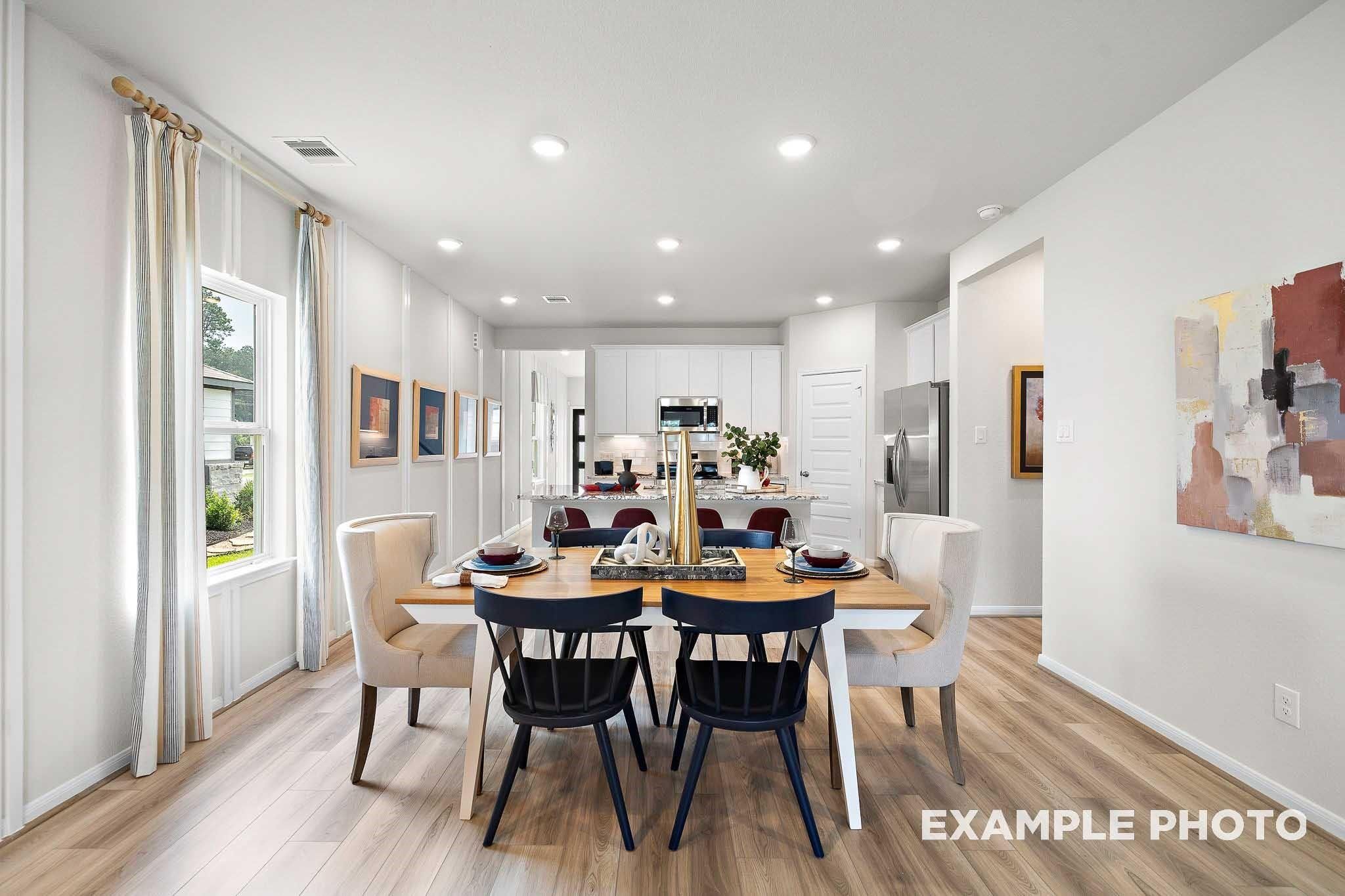 Elegant open dining area with wooden table, upholstered chairs, and kitchen island in Davidson Homes San Marcos E, Conroe TX