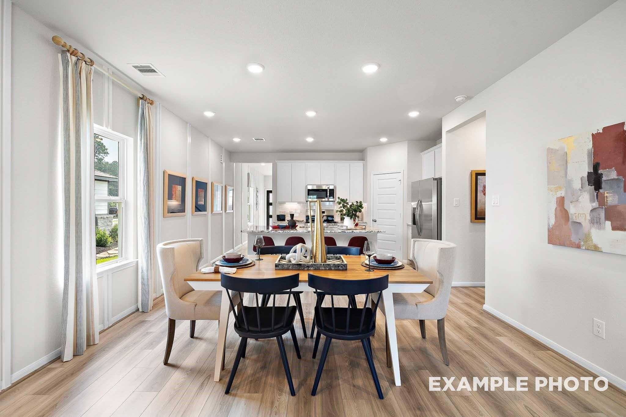 Elegant open dining area with wooden table, upholstered chairs, and kitchen island in Davidson Homes San Marcos E, Conroe TX