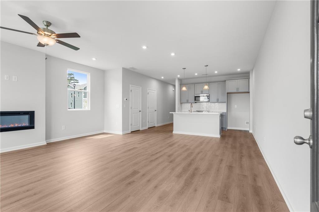 Spacious open living room with linear gas fireplace, white kitchen island, hardwood floors, and large window in Davidson Homes The Monroe B, Emerson, GA