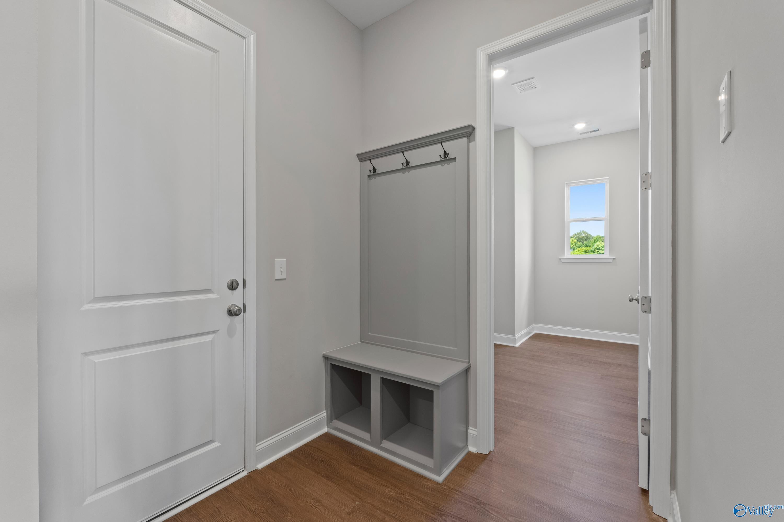 Mudroom with gray walls, built-in bench, coat hooks, and storage cubbies in The Arcadia B, Davidson Homes, Huntsville, AL