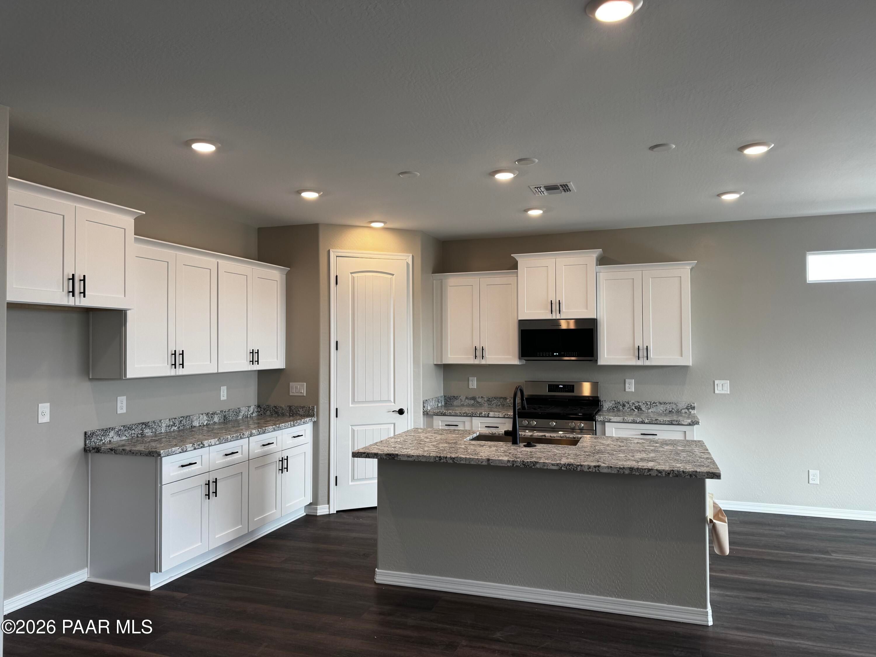 Modern kitchen featuring white shaker cabinets, granite countertops, center island, and stainless appliances in Davidson Homes Durango II B, Prescott AZ