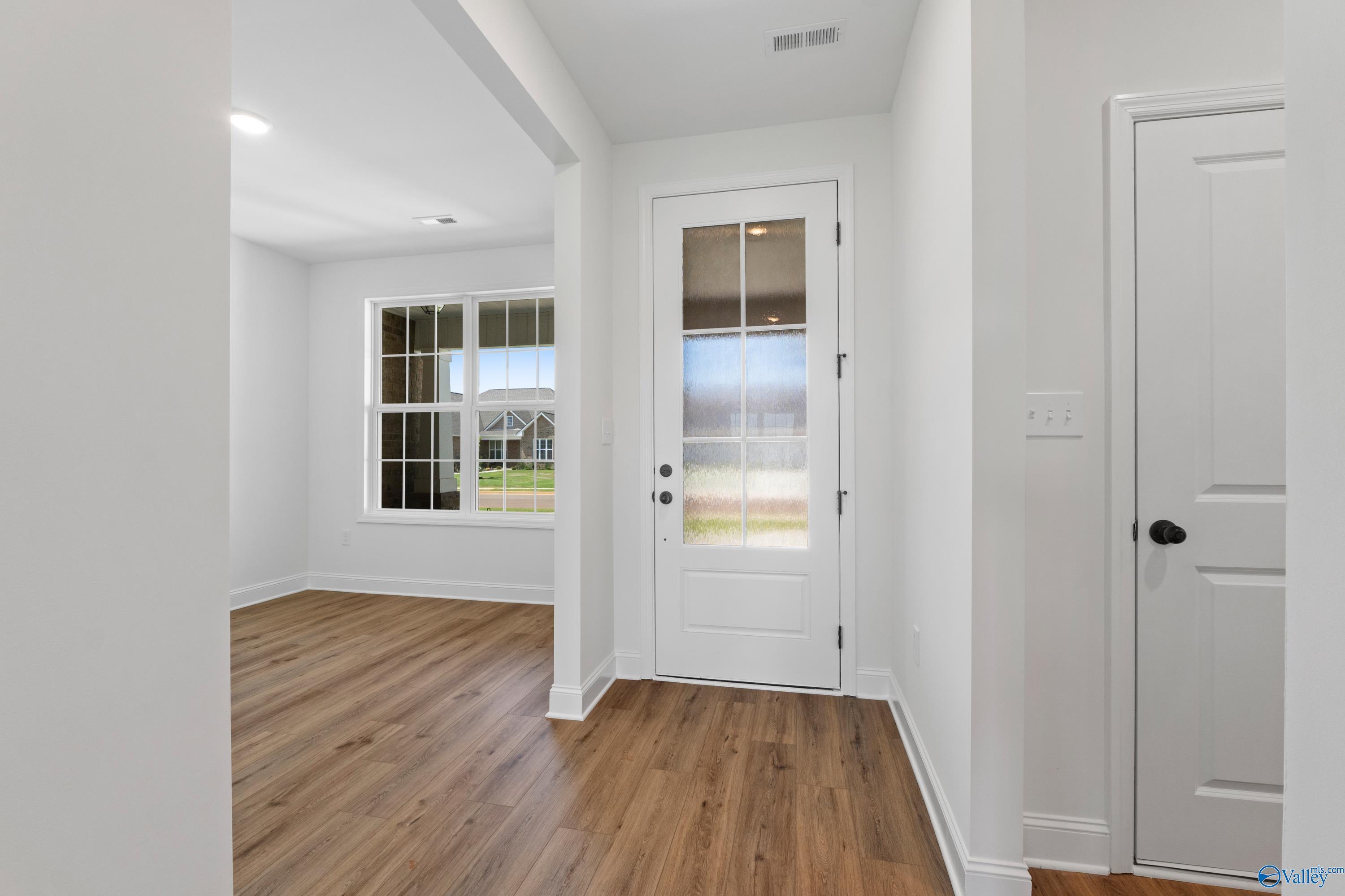 Bright entry foyer with glass-paneled door, hardwood floors, and natural light in Davidson Homes The Rockford B, Toney, Alabama