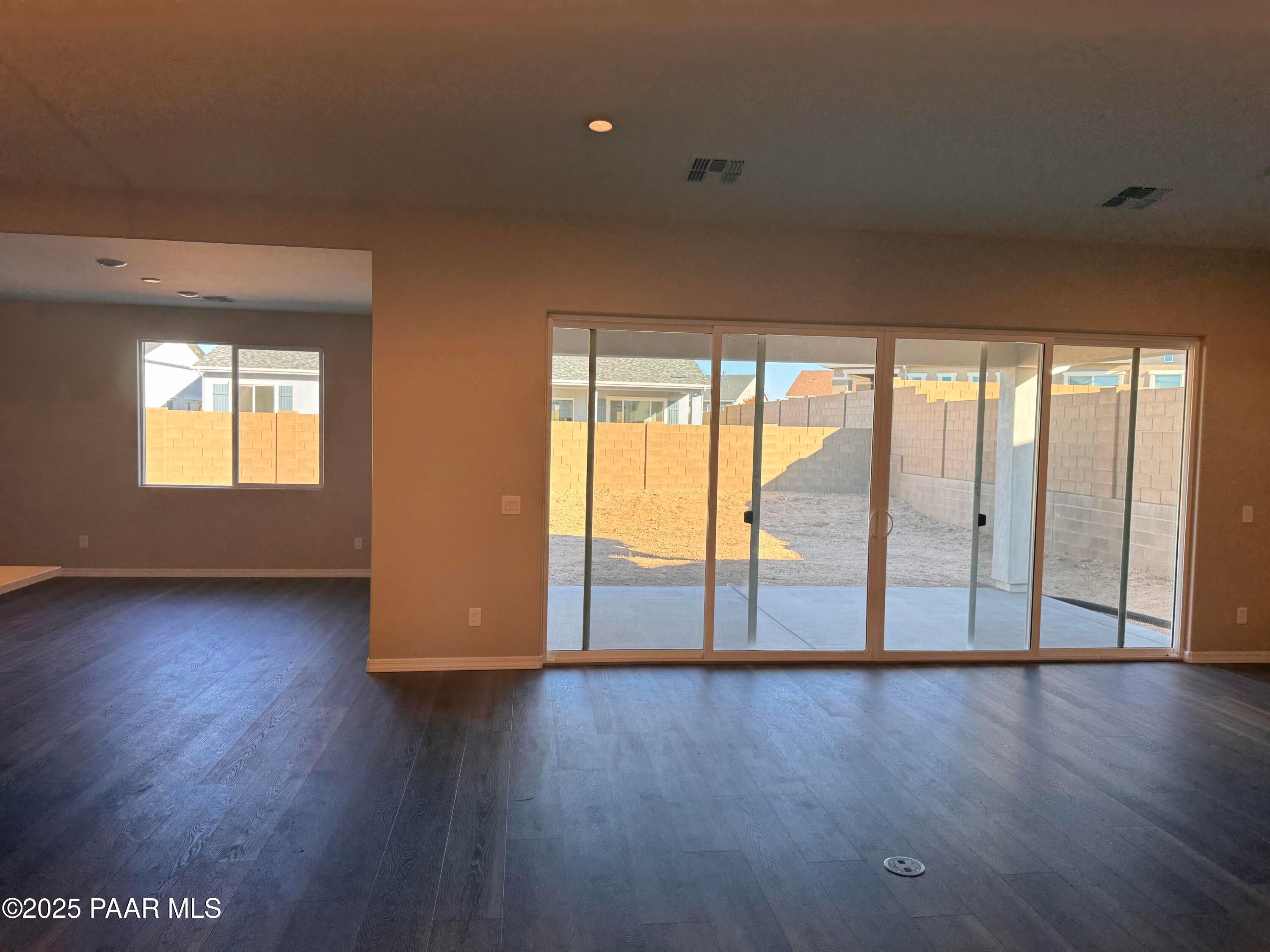 Spacious living area with dark laminate floors and sliding glass doors to backyard patio in Davidson Homes The Sunrise II A, Prescott Arizona