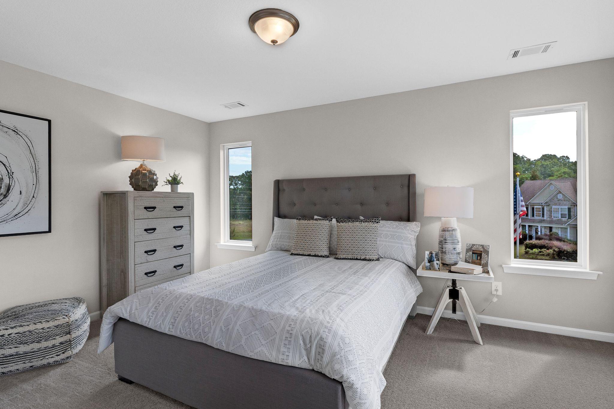 Spacious bedroom in Ivy Glen Perry GA with gray walls tufted headboard white bedding dresser lamps and neighborhood view