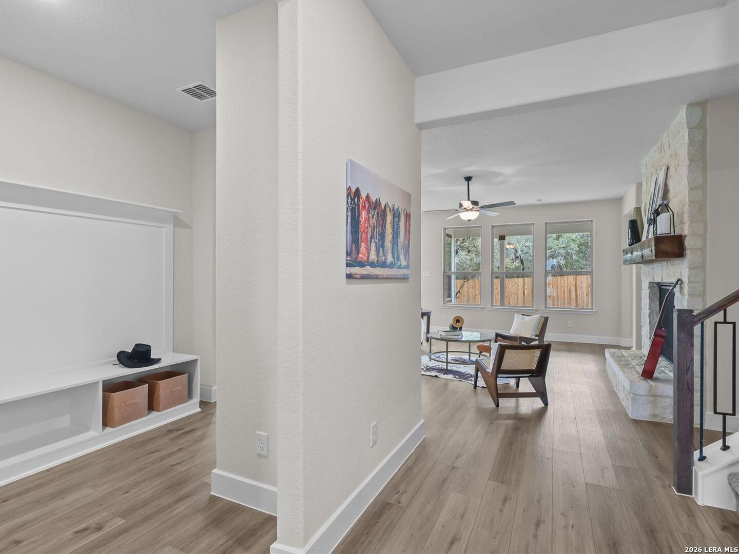Open floor plan living room with stone fireplace in The Belmont H home at Potranco Oaks, Castroville, Texas.