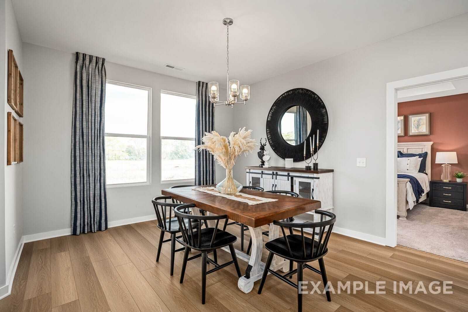 Elegant dining room with farmhouse wooden table, black chairs, chandelier, round mirror, and pampas grass in Davidson Homes The Franklin B, White House, TN