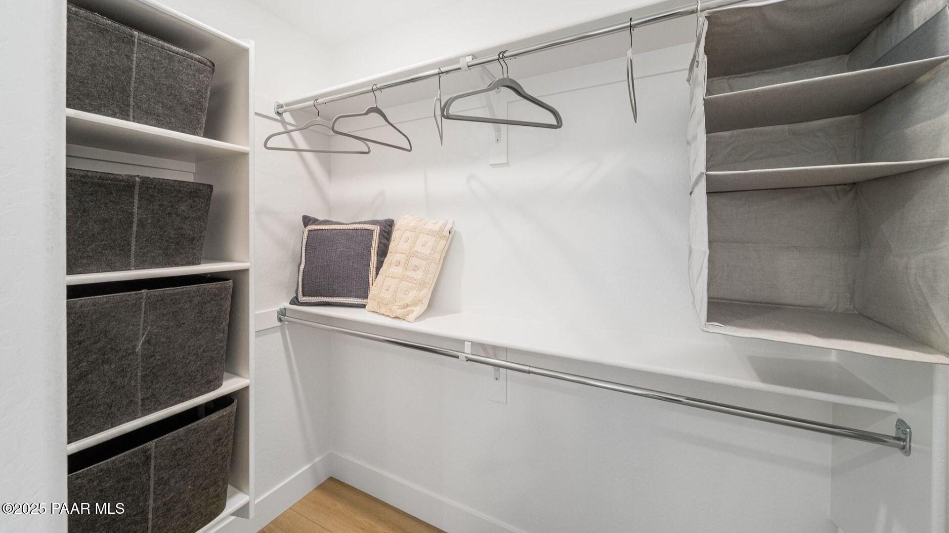 Spacious walk-in closet with built-in shelves, gray fabric bins and hanging rods in Davidson Homes The Wilmington B, Prescott, Arizona