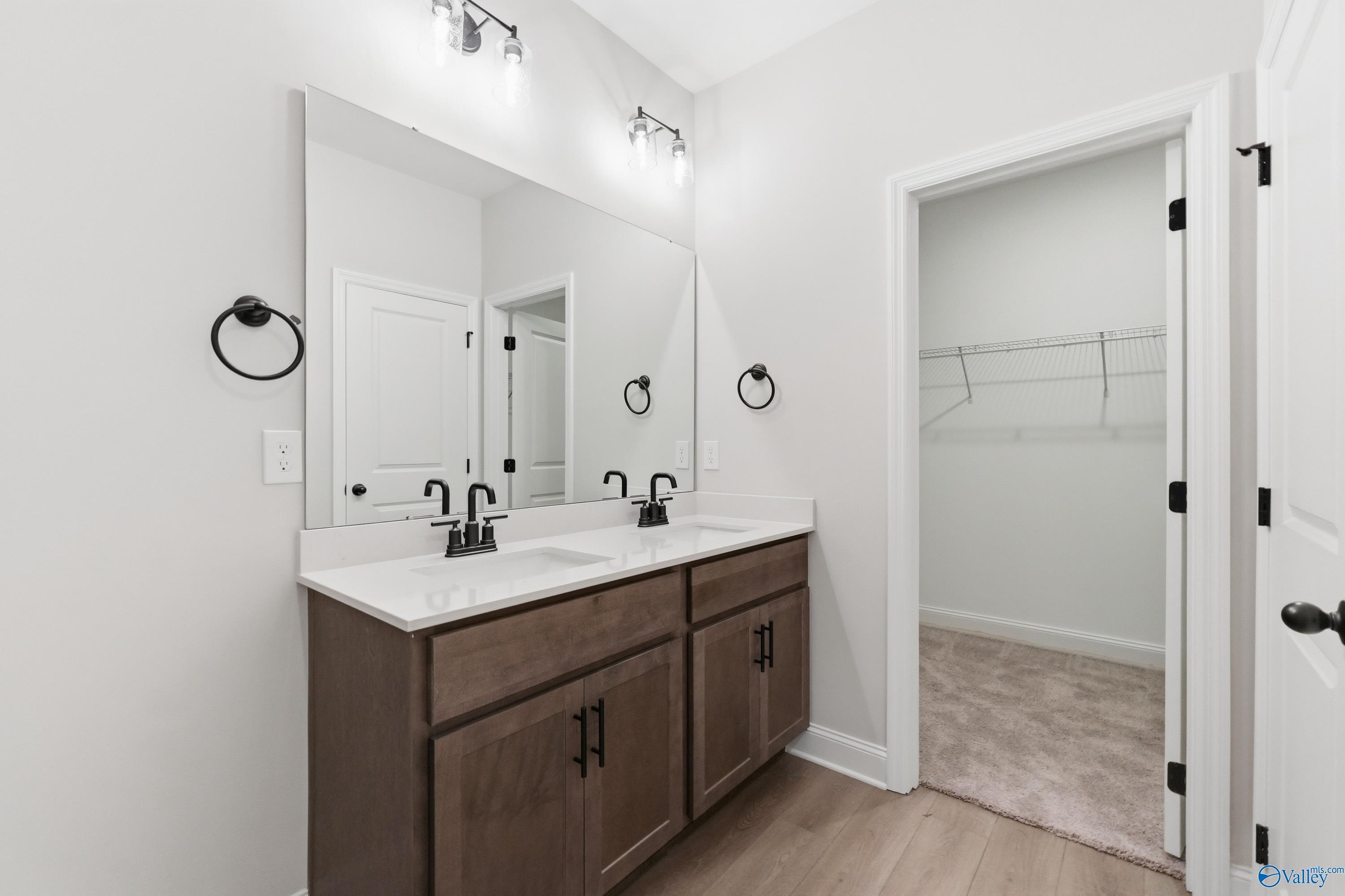 Modern master bathroom double vanity with quartz counters, dark shaker cabinets, and walk-in closet in Davidson Homes The Franklin, Huntsville AL