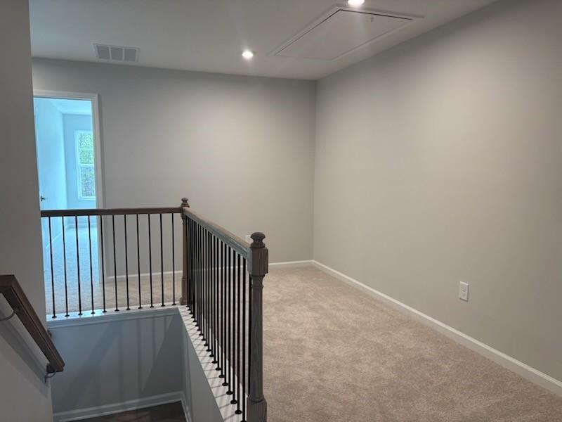 Spacious upstairs hallway with gray walls, berber carpet, and wrought iron railing in Davidson Homes The Marion A, Winder, GA