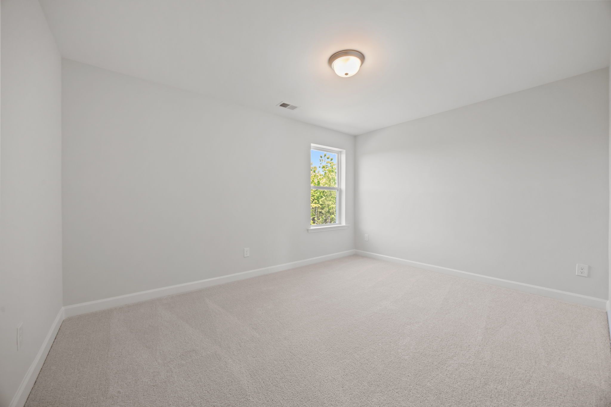 Spacious, light-filled secondary bedroom in The Ashport B floor plan featuring neutral paint and plush carpeting.