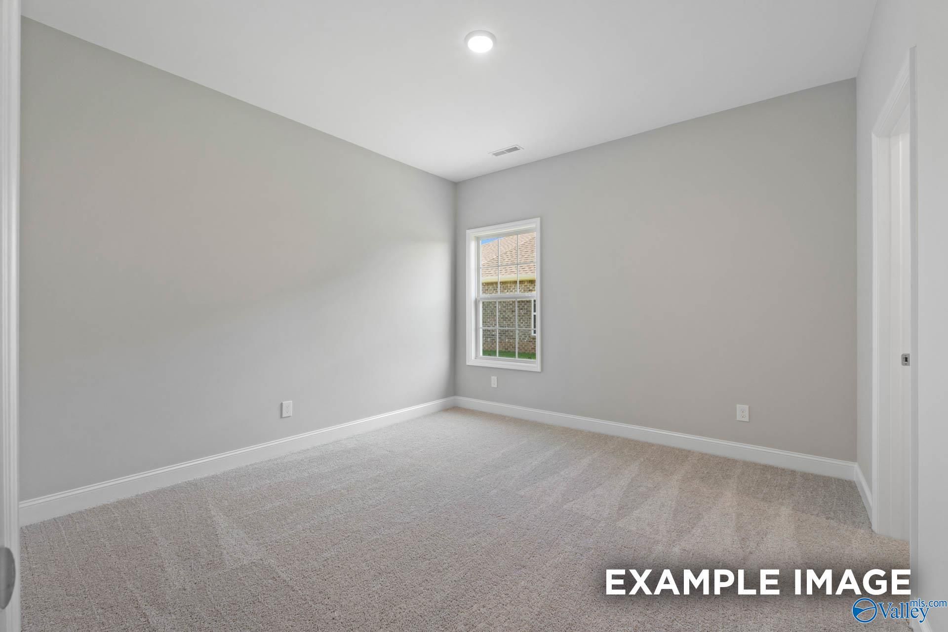 Bright secondary bedroom with gray walls, neutral carpet, and large window in Davidson Homes Montgomery B, Hartselle, Alabama
