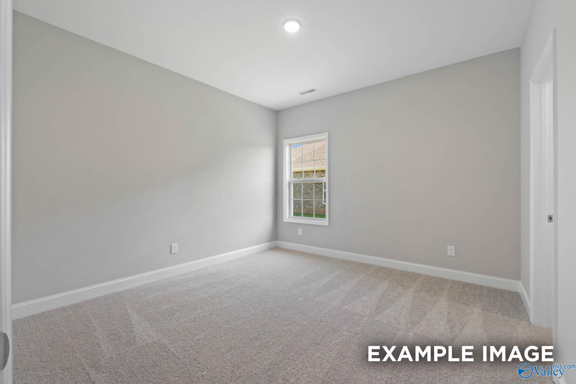Bright secondary bedroom with light gray walls, neutral carpet, large window in Davidson Homes Montgomery B, Hartselle AL