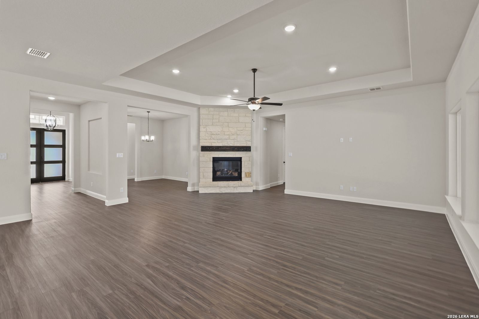 Spacious living room with stone fireplace and tray ceiling in Davidson Homes The Summerlin B, Potranco Oaks, Castroville.