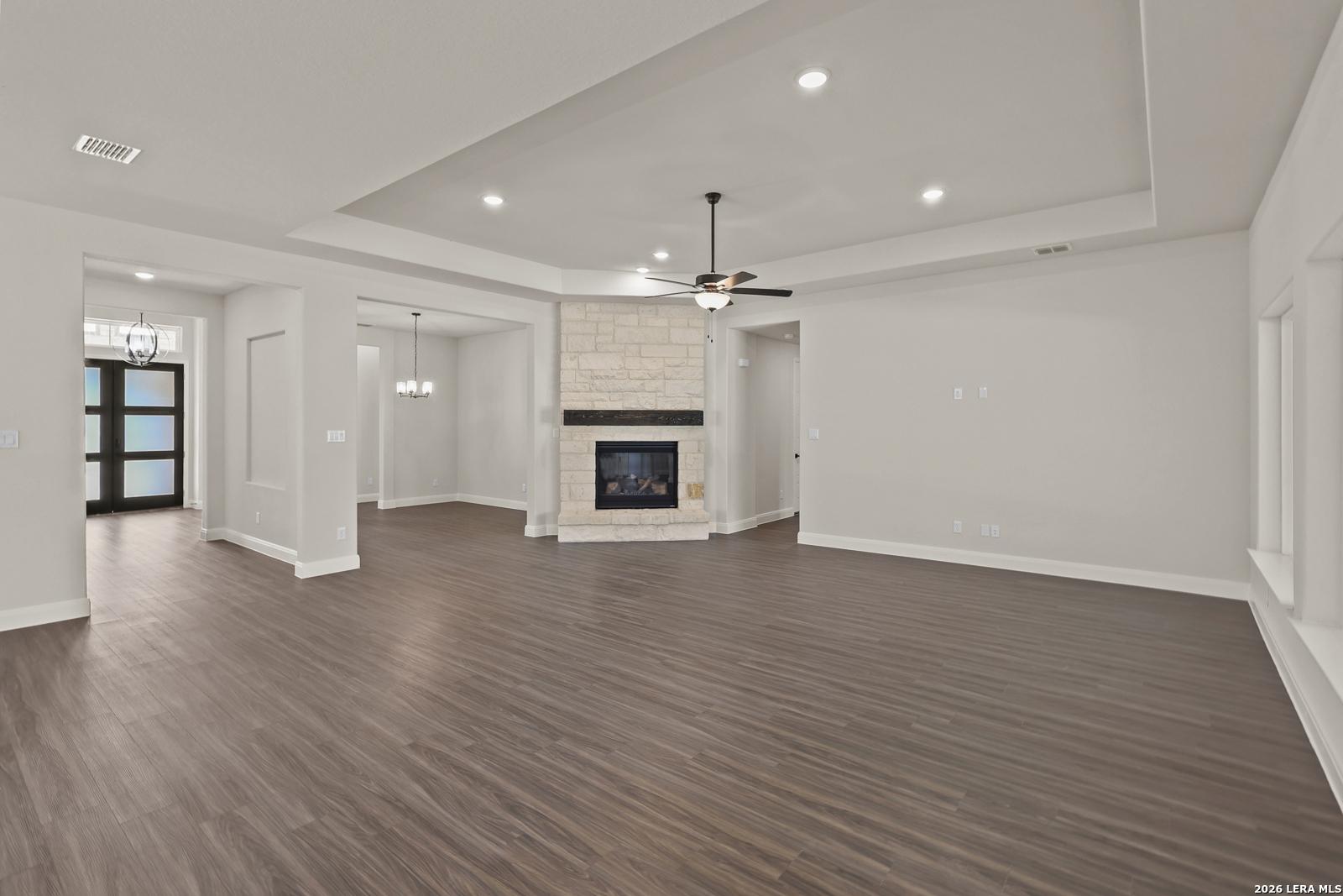 Spacious living room with stone fireplace and tray ceiling in Davidson Homes The Summerlin B, Potranco Oaks, Castroville.