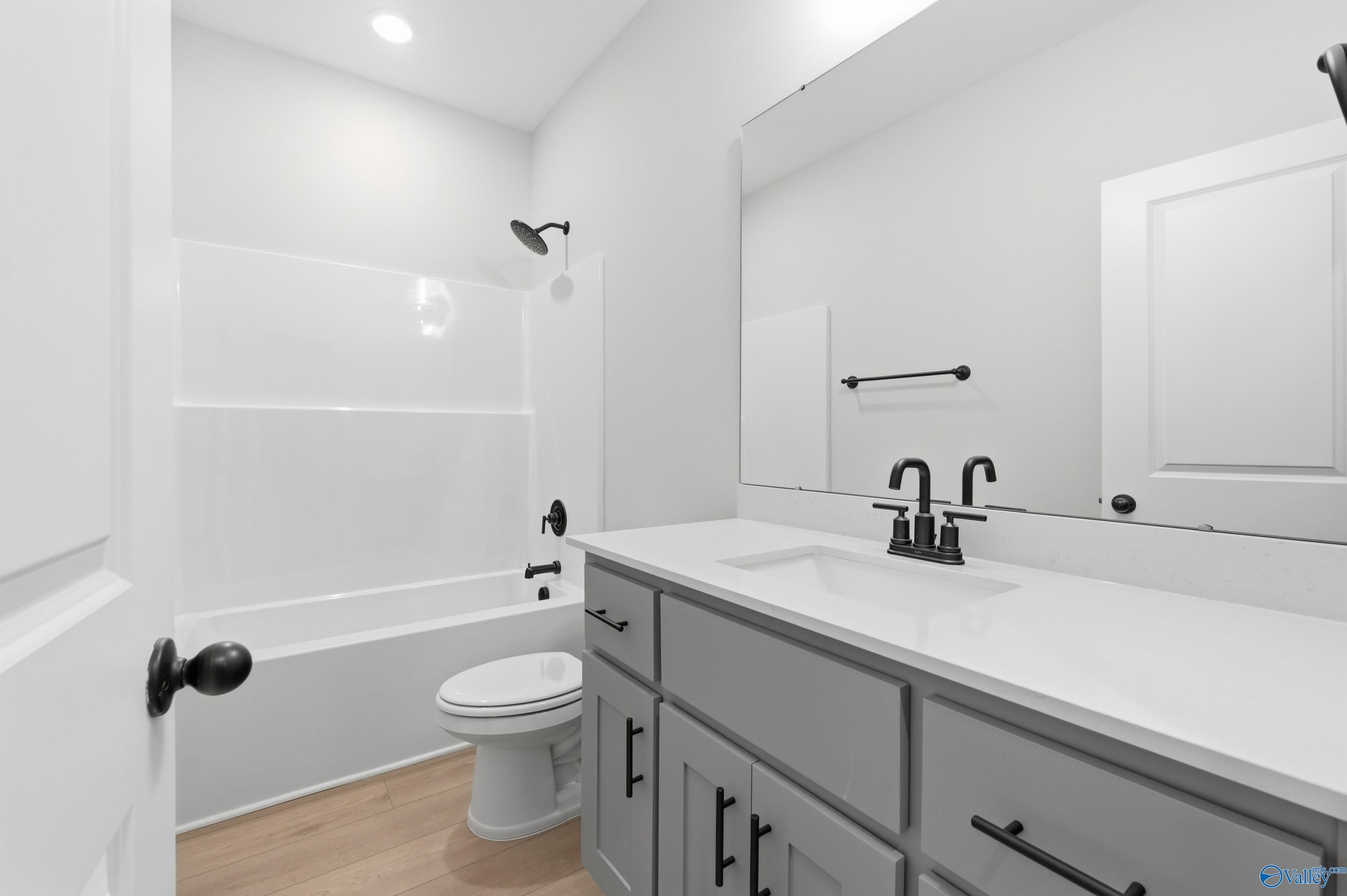 Modern bathroom with white subway tile tub-shower, gray shaker vanity, sink, toilet in Davidson Homes The Daphne C, Athens AL