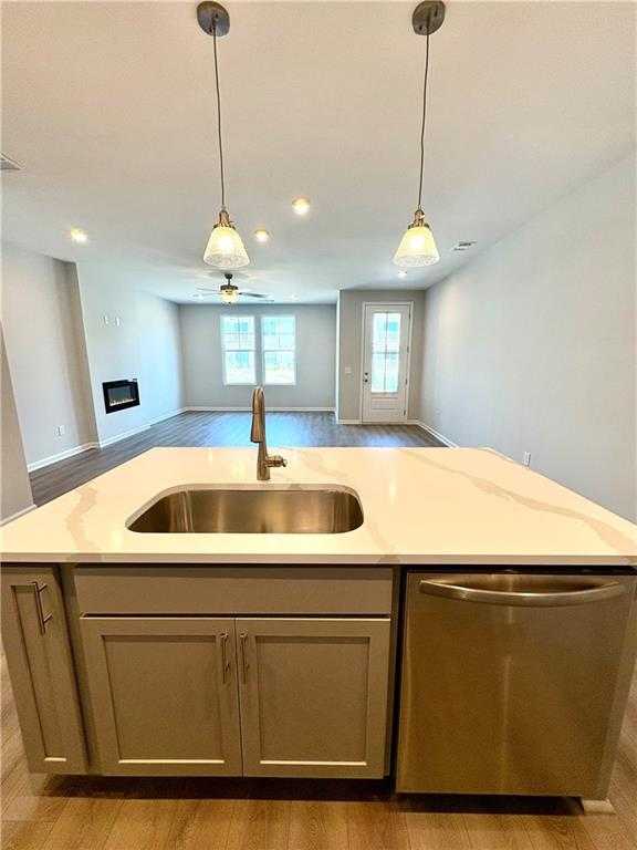 Open-concept kitchen with quartz island, stainless sink and dishwasher in The Monroe B, Davidson Homes, Emerson, Georgia