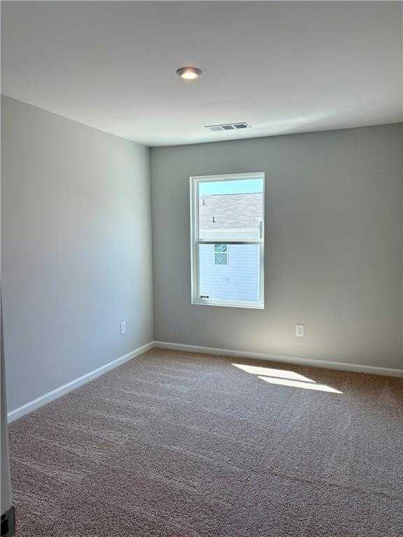Bright empty bedroom with light gray walls, beige carpet floor, and sunlit window in Davidson Homes The Monroe B, Emerson, Georgia