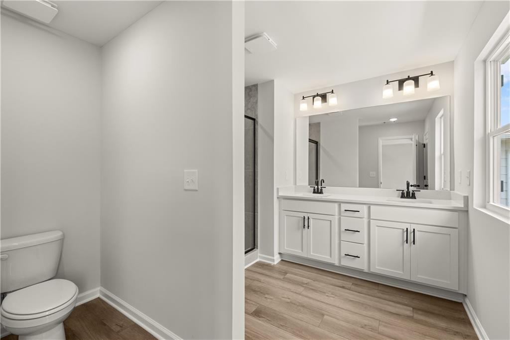 Modern primary bathroom with white double vanity and LVP flooring in The Hartwell A floor plan at The Bluffs, Canton, GA.