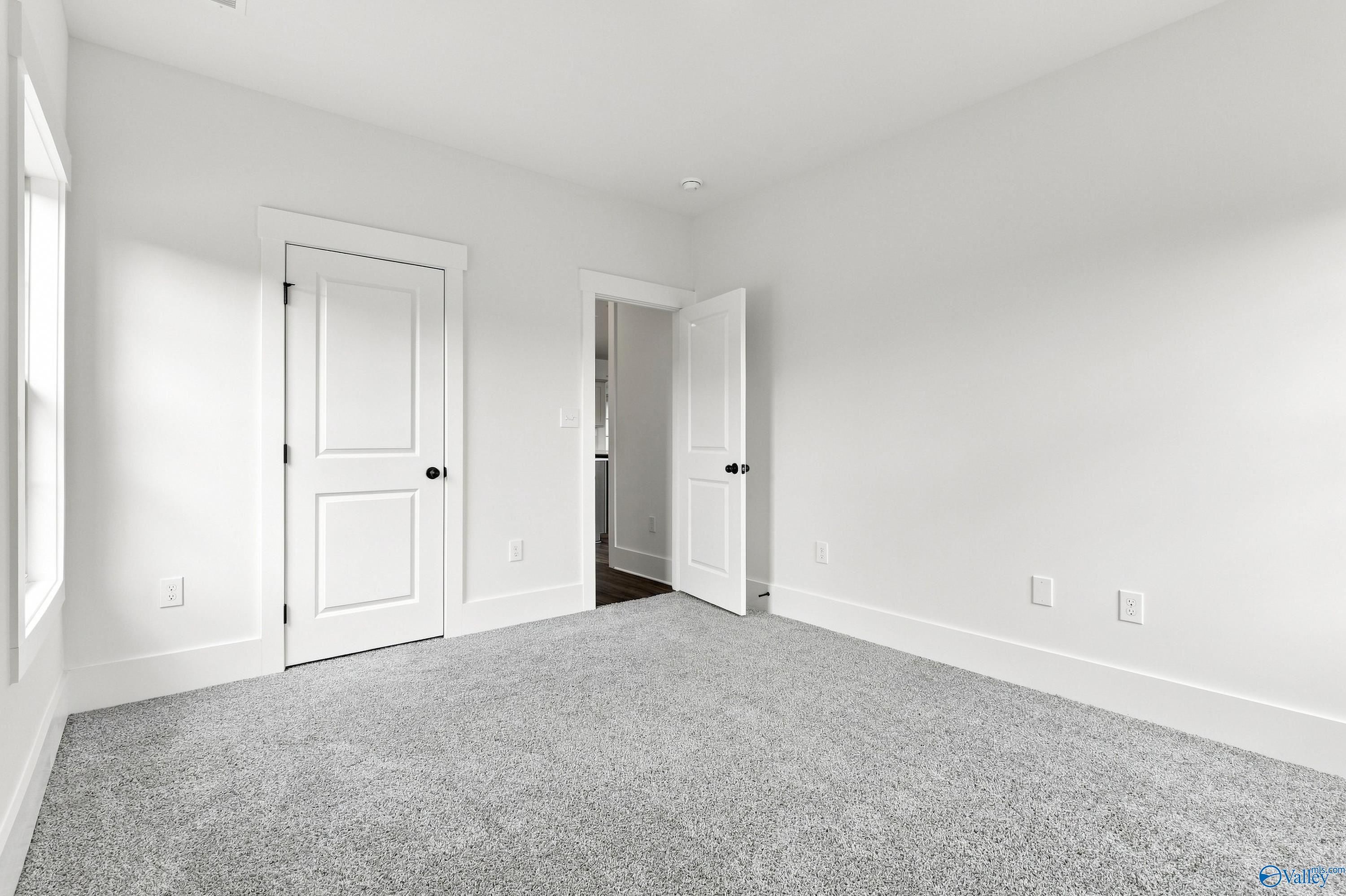 Bright bedroom with new carpet, white doors, and black hardware in Davidson Homes' The Valencia, Riverton Preserve, Huntsville, AL