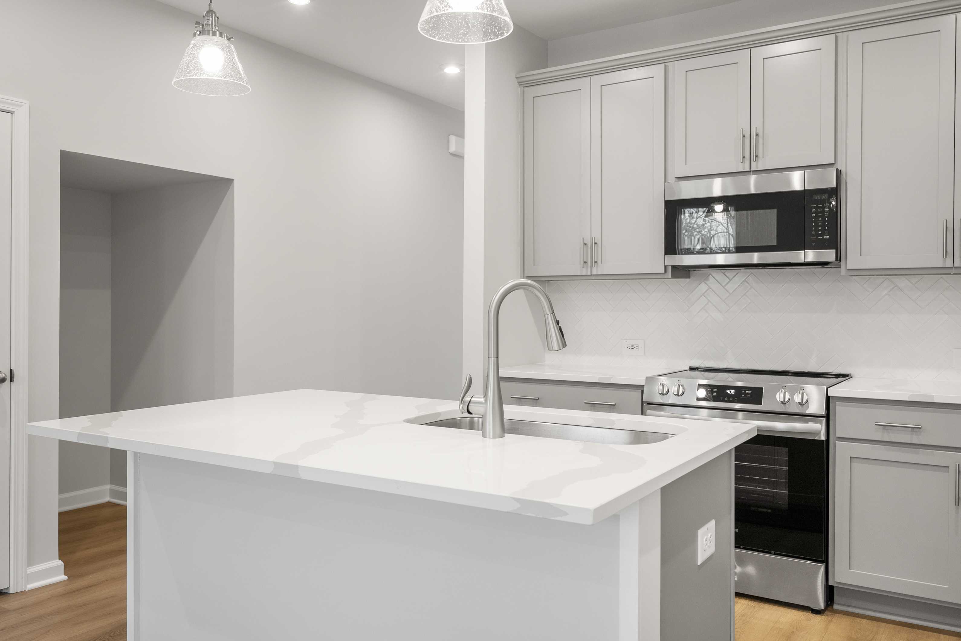 Modern kitchen in The Durant A by Davidson Homes featuring white shaker cabinets, quartz island, stainless appliances