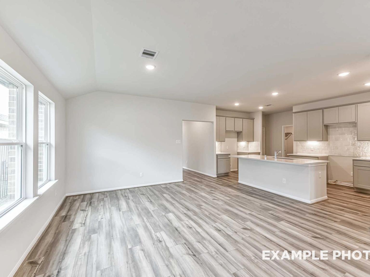 Open-concept living room and kitchen with wood-look flooring at The Laguna C floor plan in River Ranch Meadows, Dayton.