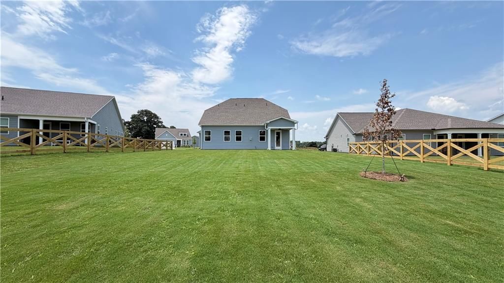 Large grassy backyard with wooden fence behind The Ash C floor plan home at Wehunt Meadows in Hoschton, Georgia.