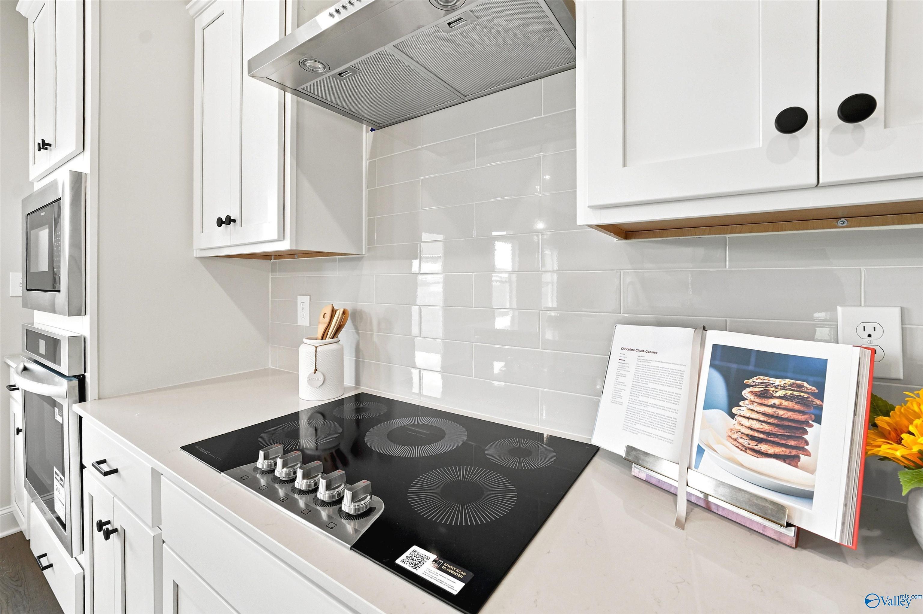 Modern kitchen with electric cooktop, subway tile backsplash, and white cabinetry in The Burton B floor plan, New Market, AL.