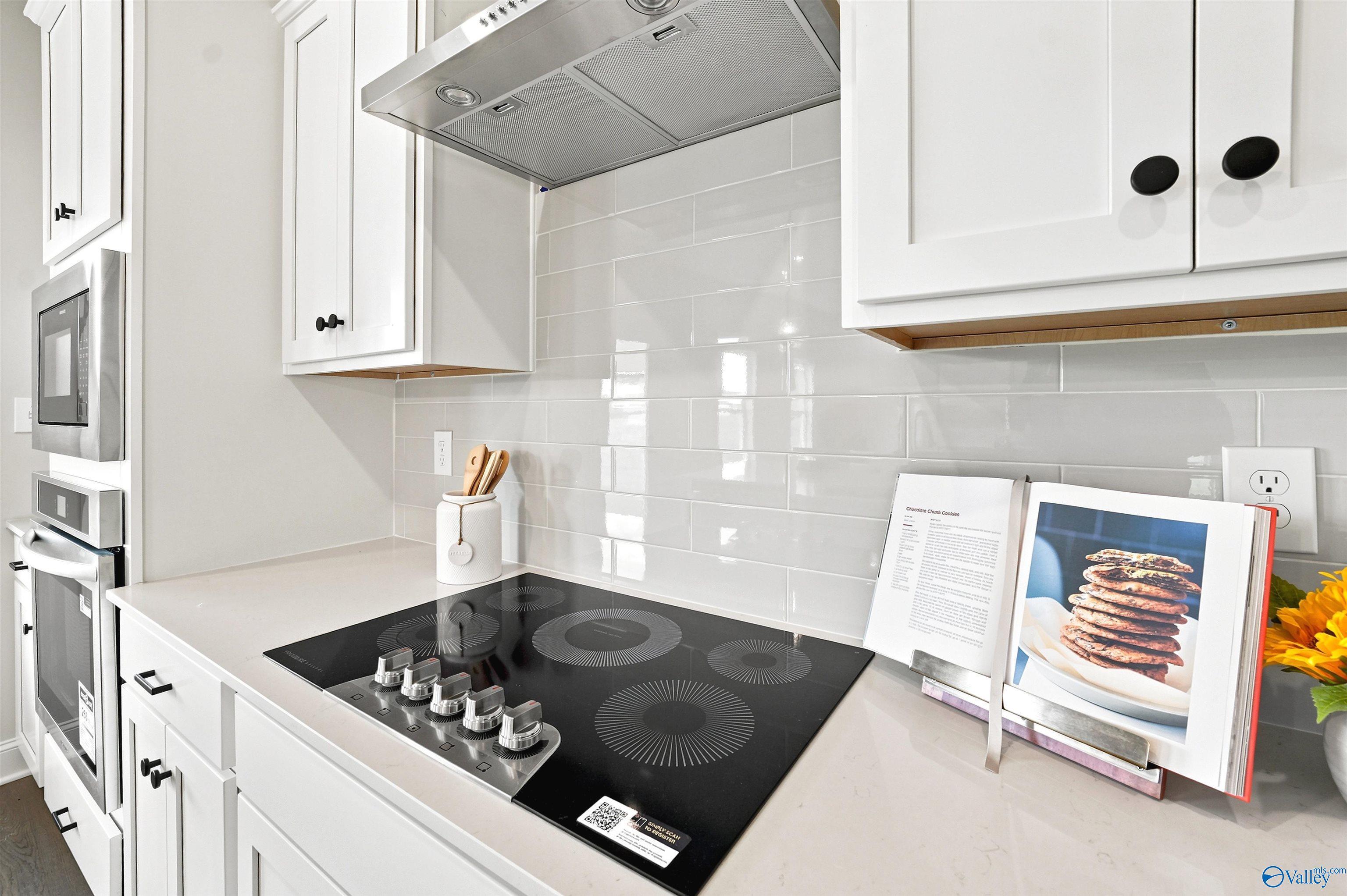 Modern kitchen with electric cooktop, subway tile backsplash, and white cabinetry in The Burton B floor plan, New Market, AL.