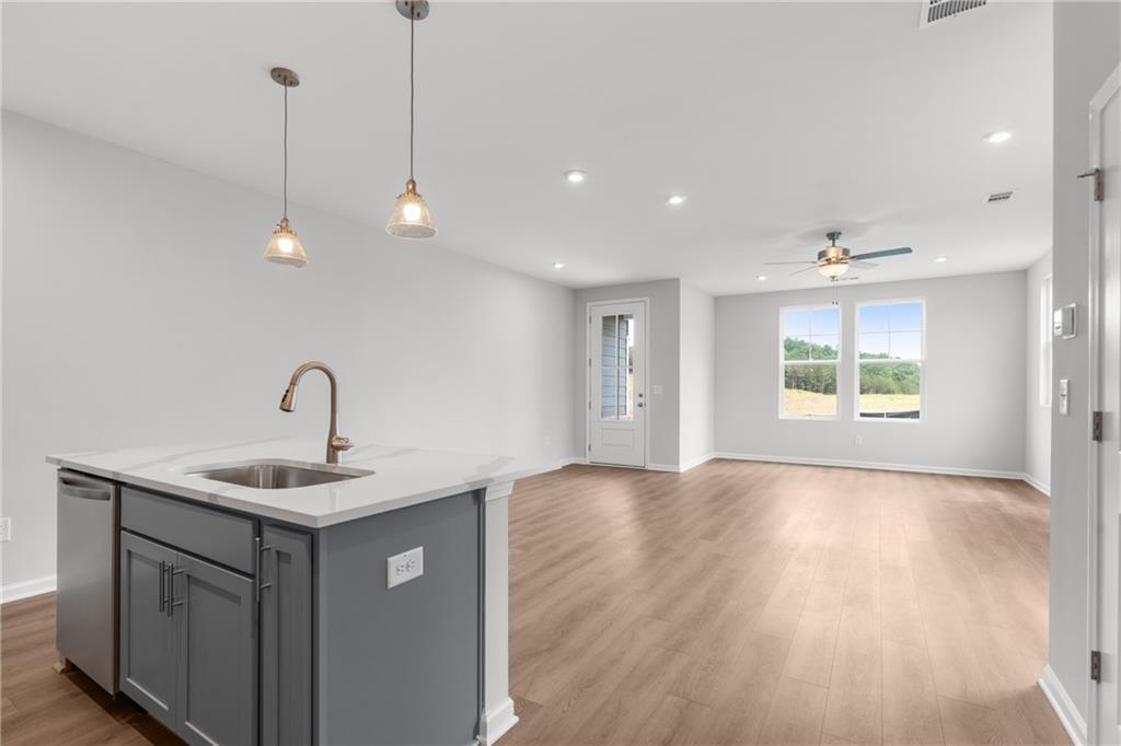 Open-concept kitchen with gray island, quartz countertop, bronze faucet, and hardwood floors in The Monroe B by Davidson Homes, Emerson, Georgia
